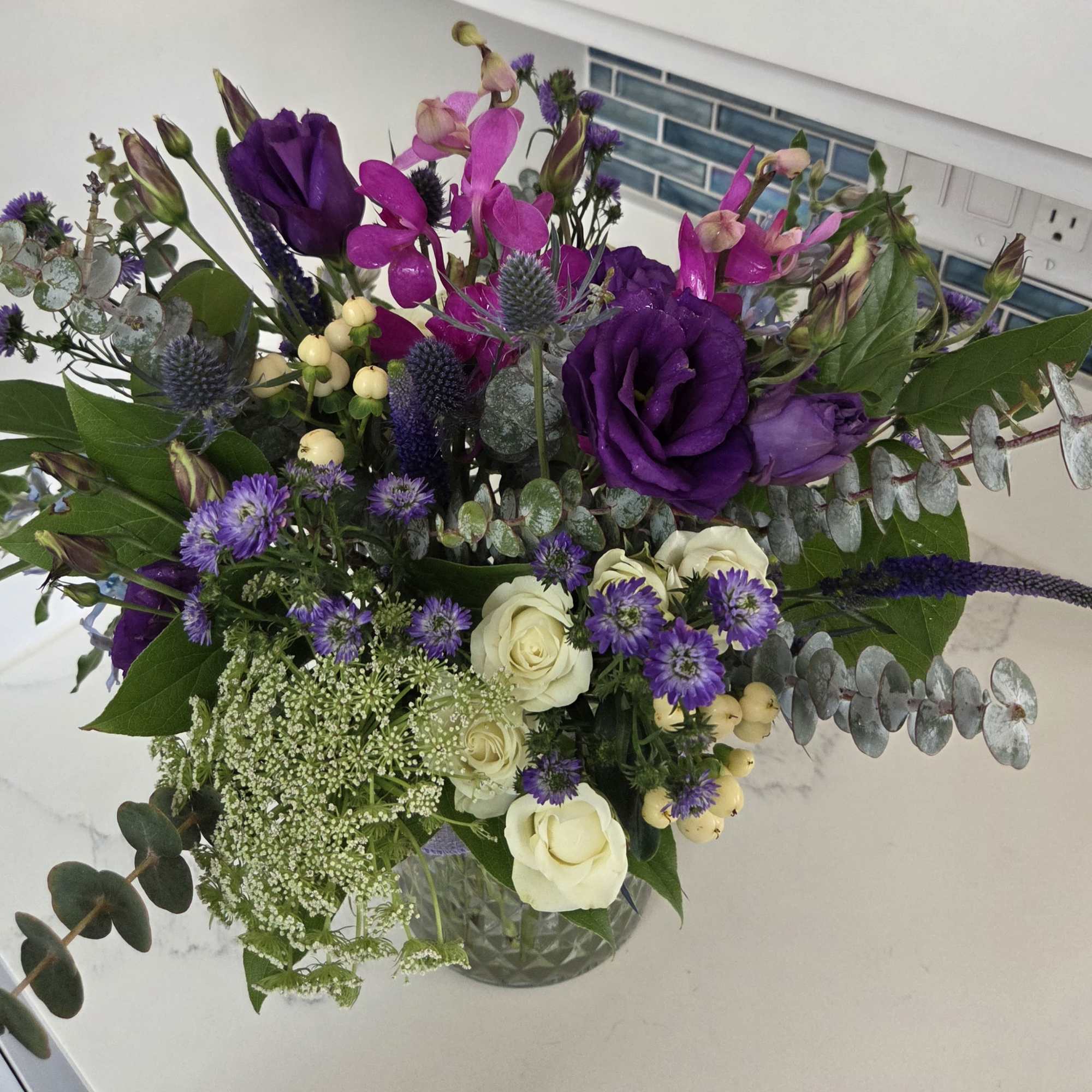 This floral arrangement features rich, moody shades of blue, purple and green, photo 2 of 2