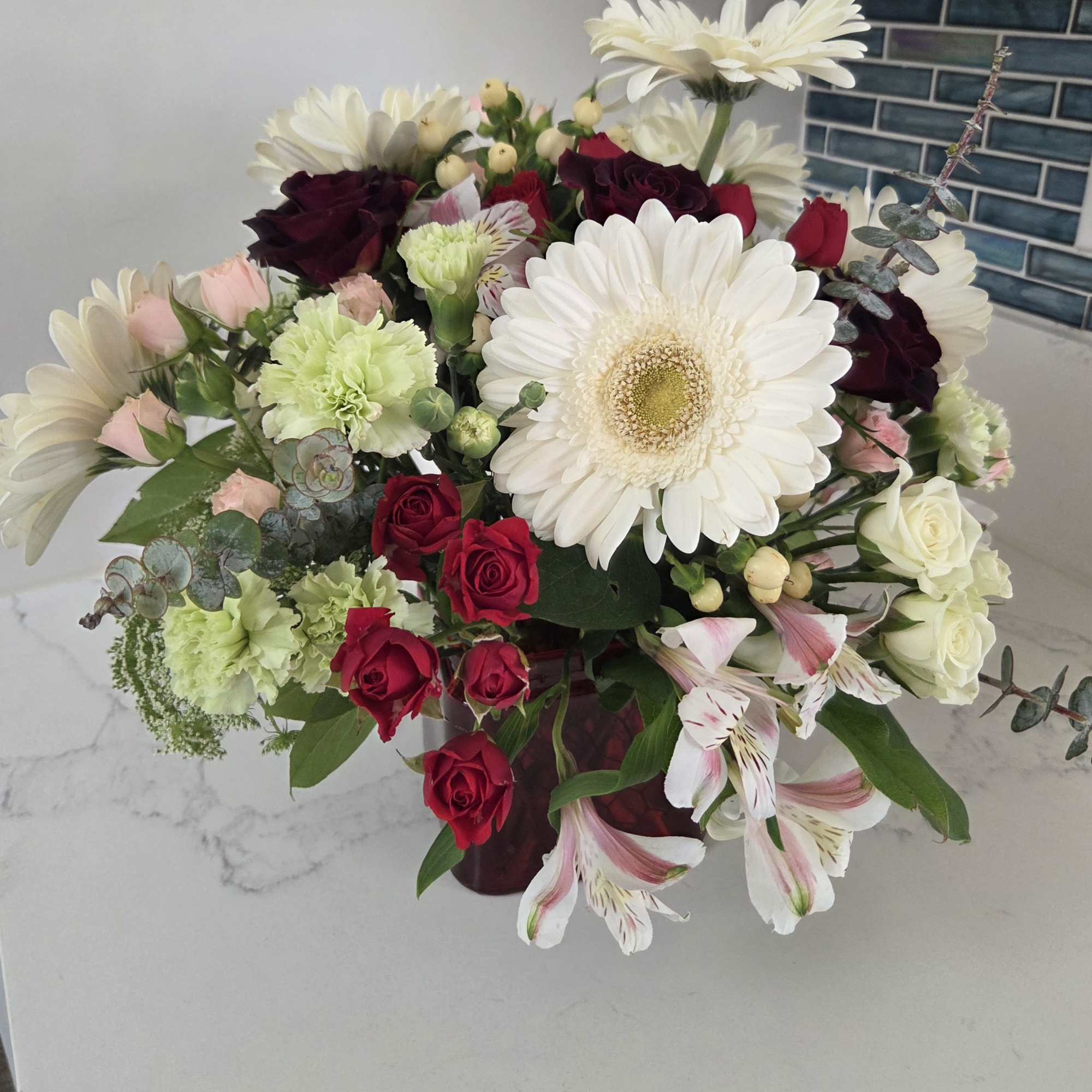 A delightful white and green bouquet with a touch of red or