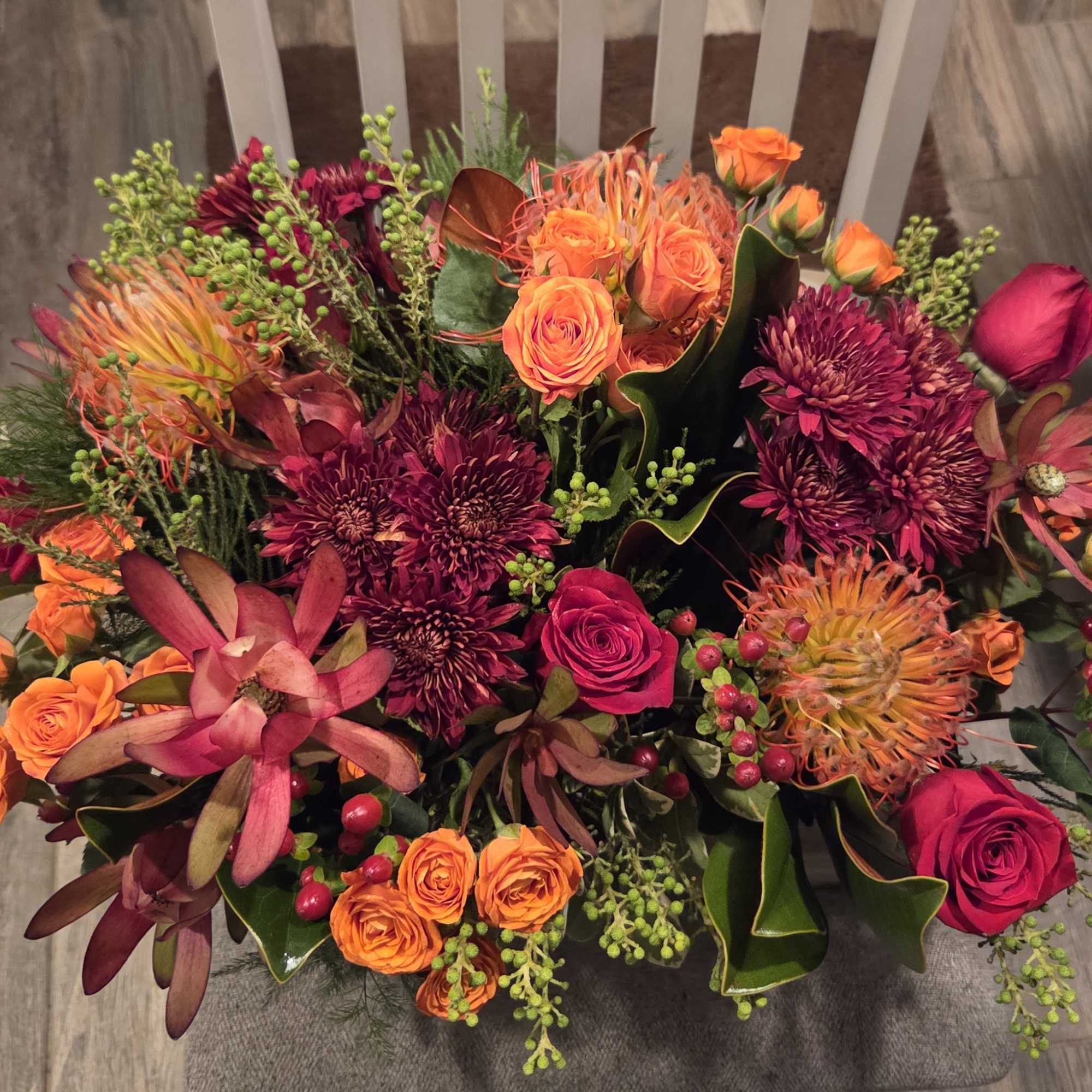 Mixed bouquet of orange and magenta flowers with berries and dark foliage