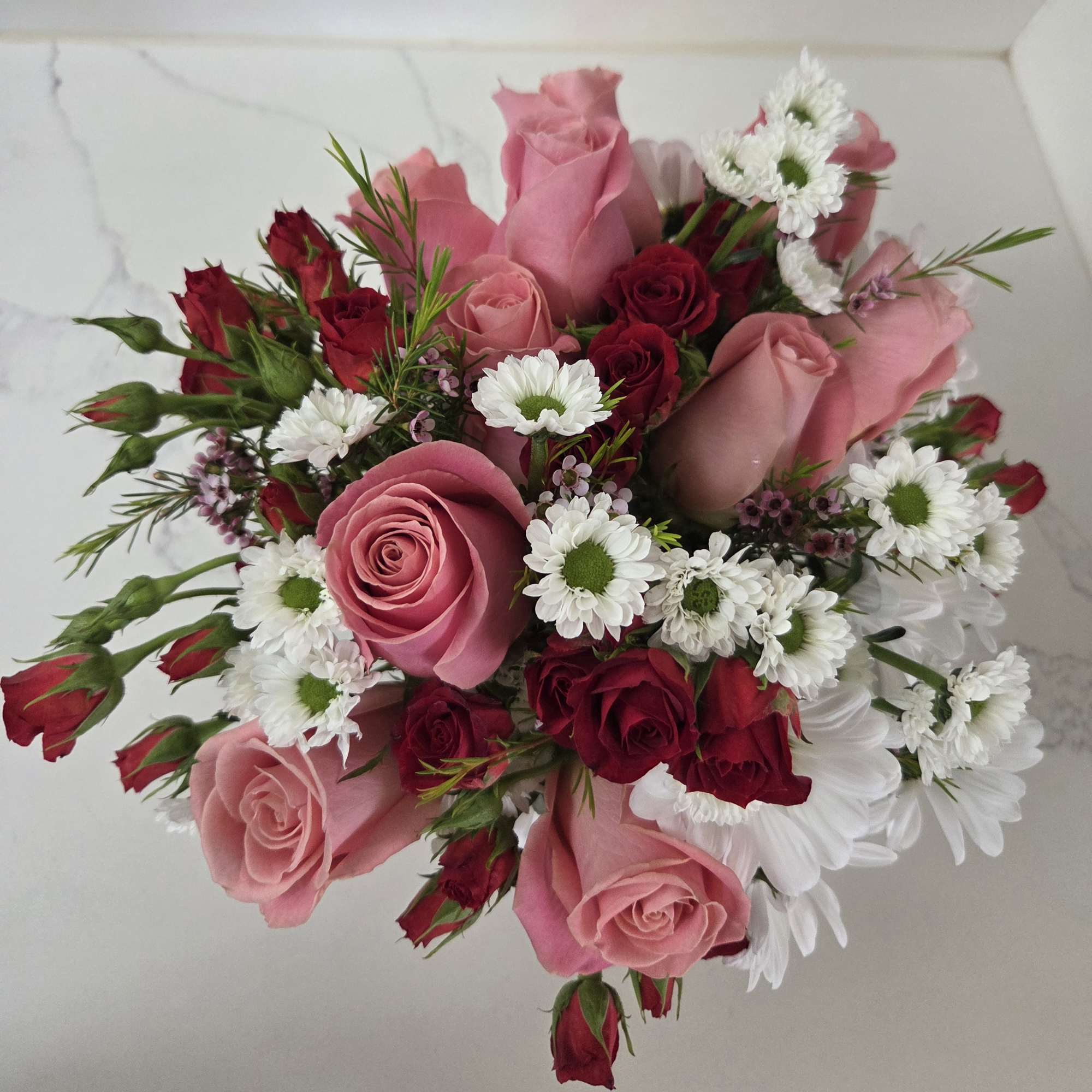 Bouquet of pink and red roses with white daisy flowers