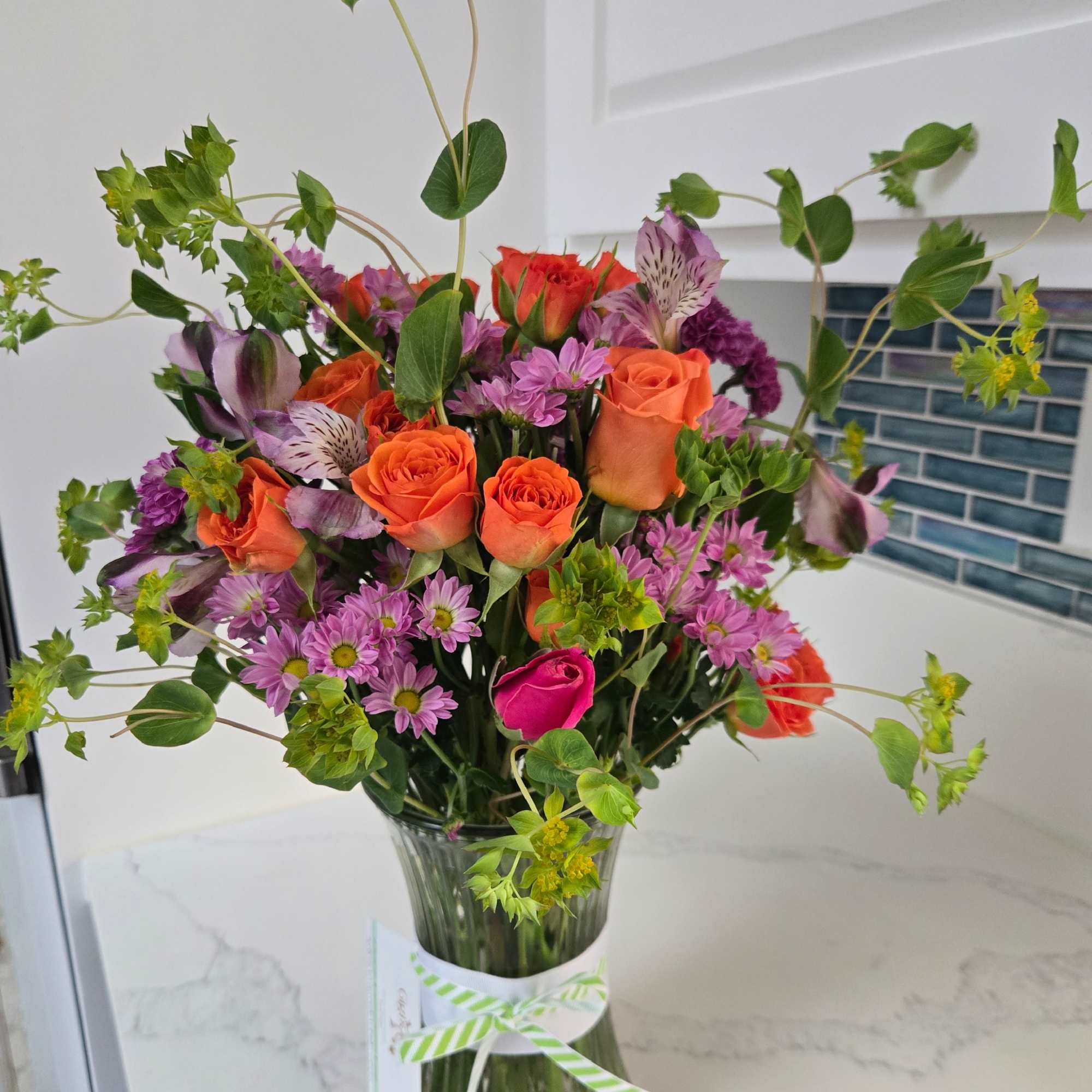 Mixed bouquet of orange and pink flowers in a glass vase
