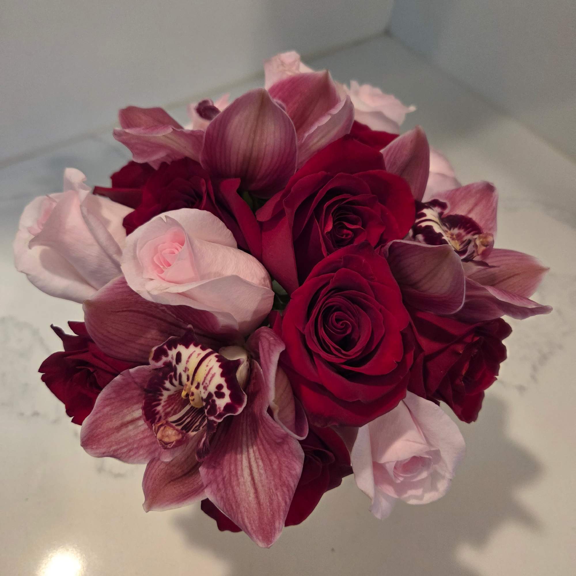 Bouquet of red and pale pink roses with pink orchids