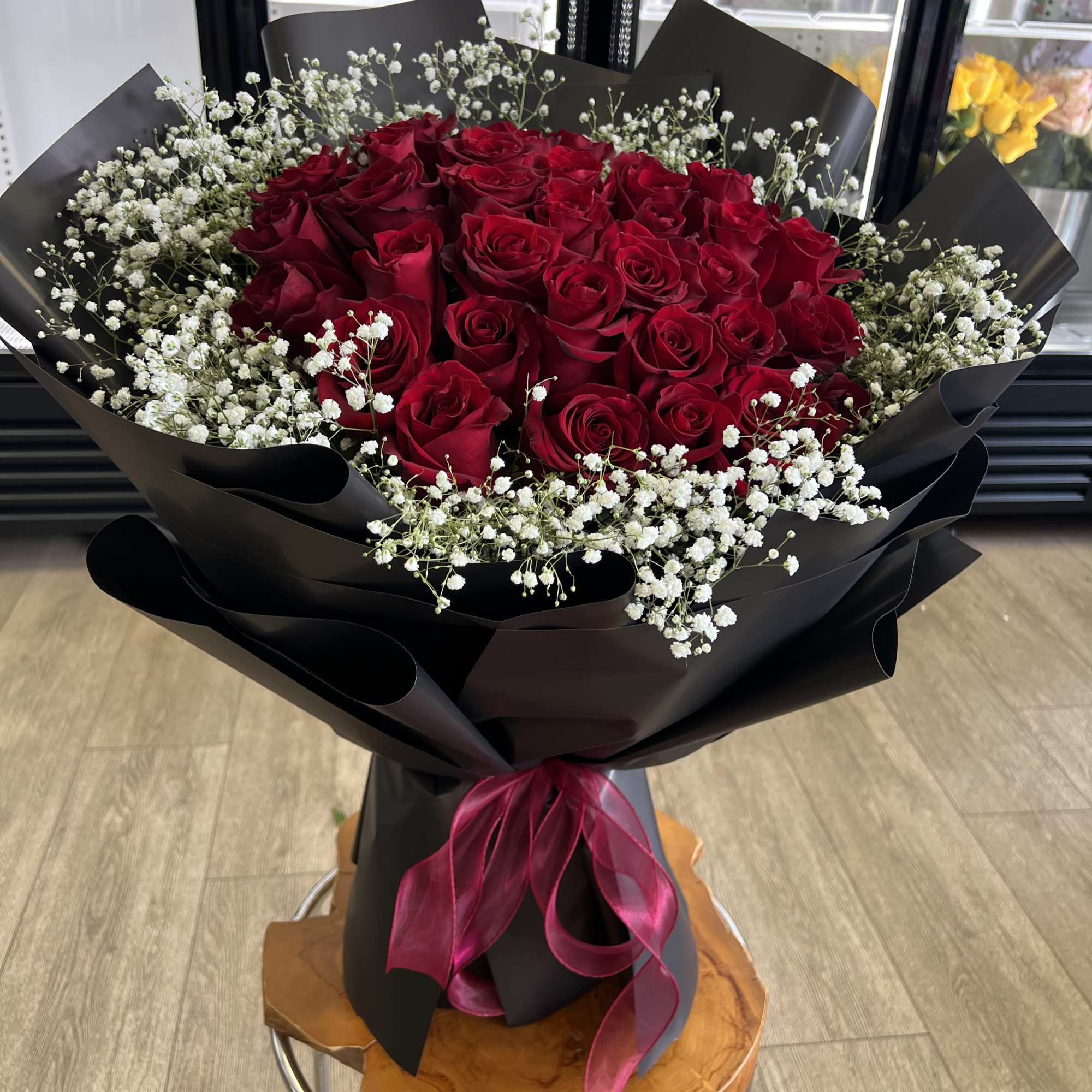 Bouquet of red roses with white baby's breath in black wrap and pink ribbon
