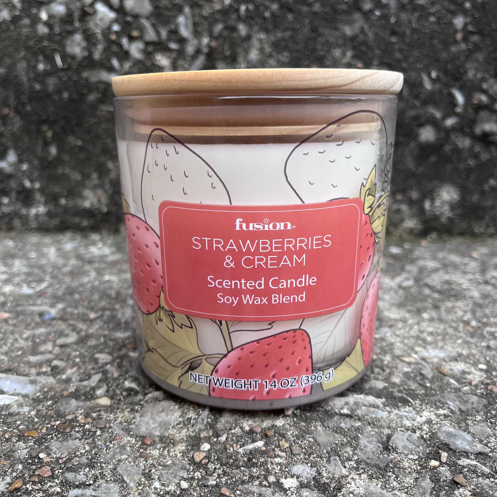 Strawberries and cream scented candle in a glass jar with a wooden lid
