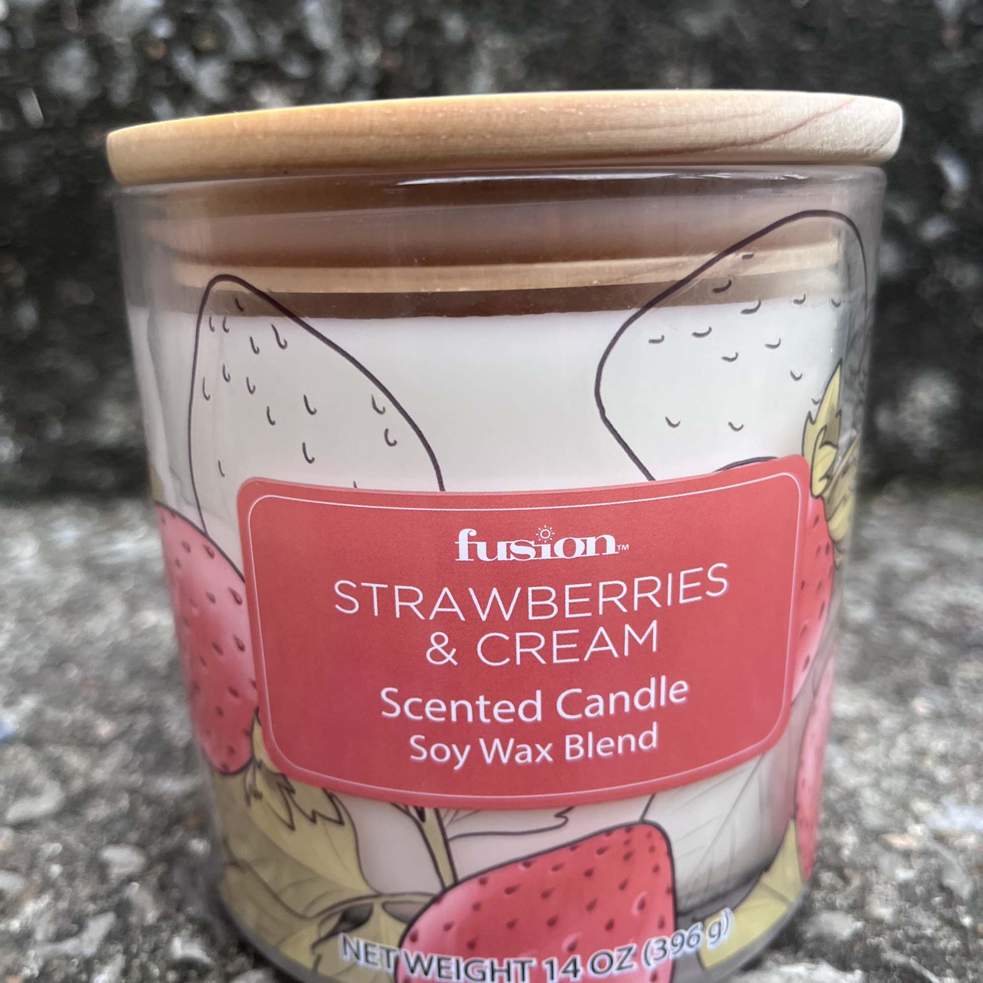 Strawberries and cream scented candle in a glass jar with a wooden lid