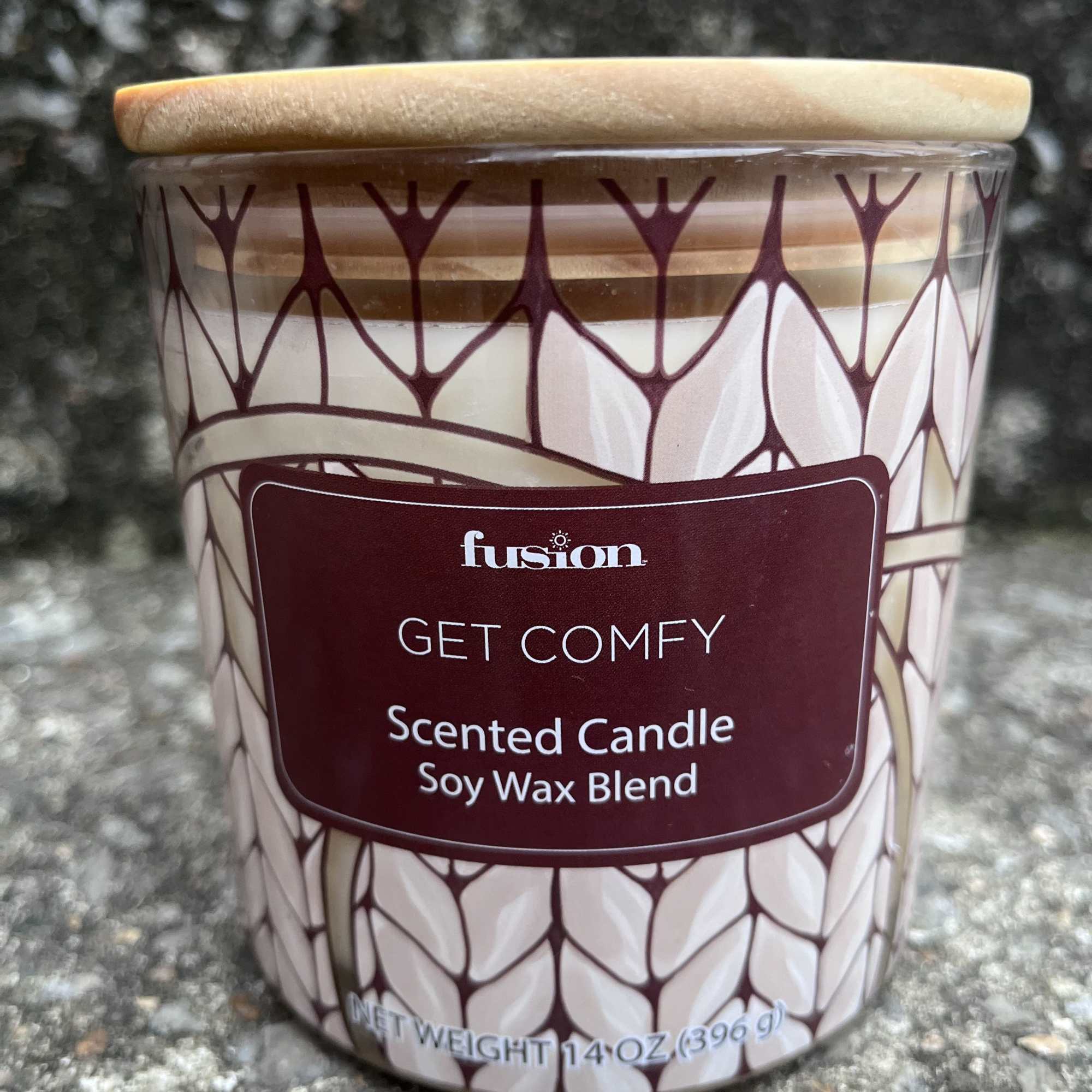 Scented candle in a patterned glass jar with a wooden lid