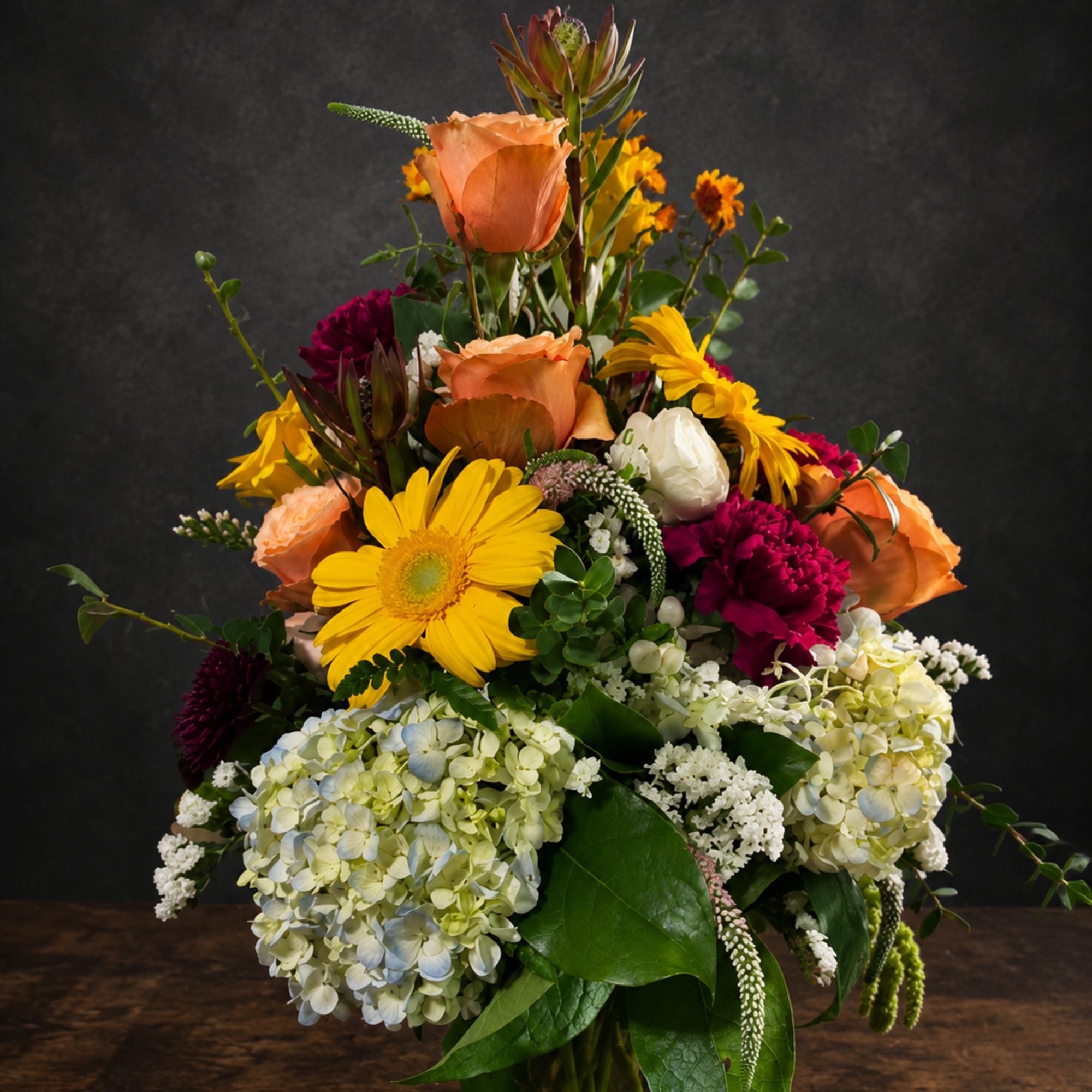 Bright yellow gerbera daisies and soft peach roses create an immediate burst