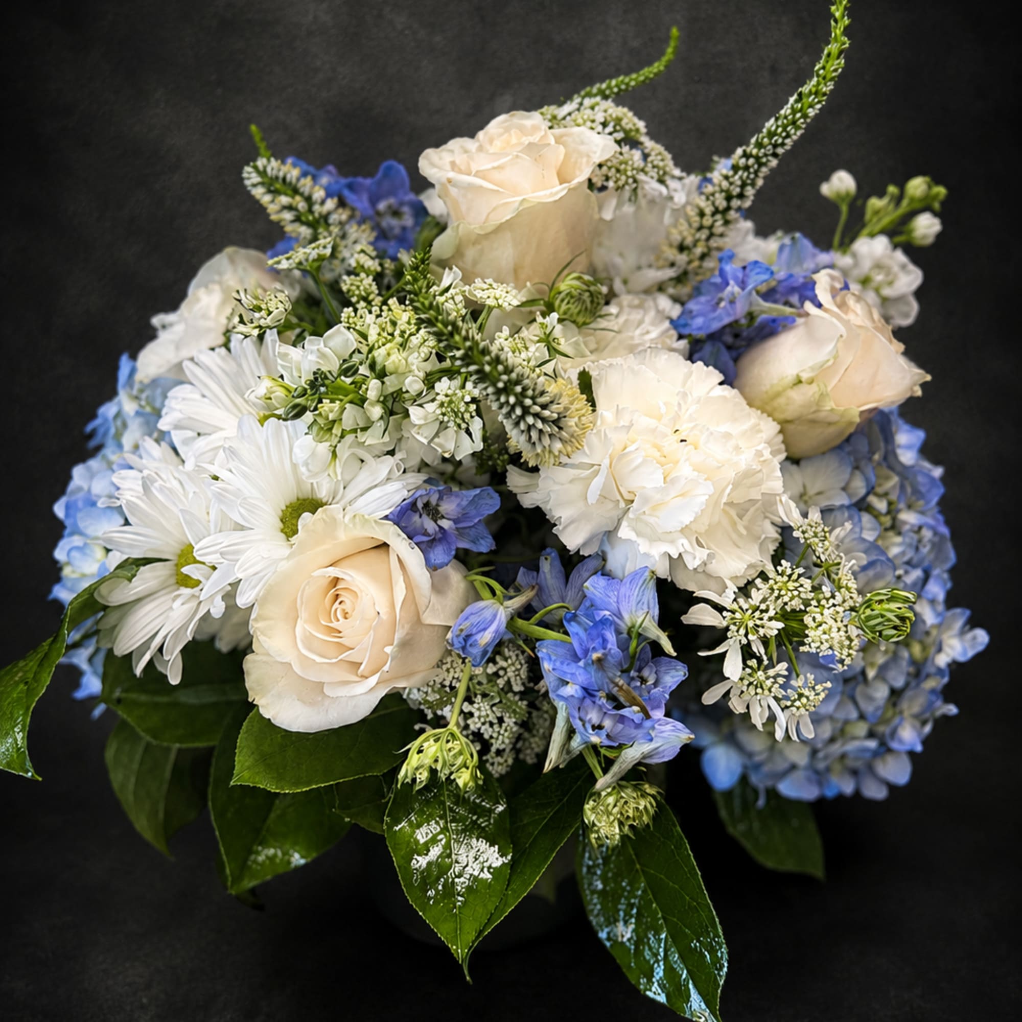 Cream roses and airy blue hydrangeas create a calm, garden-fresh impression in