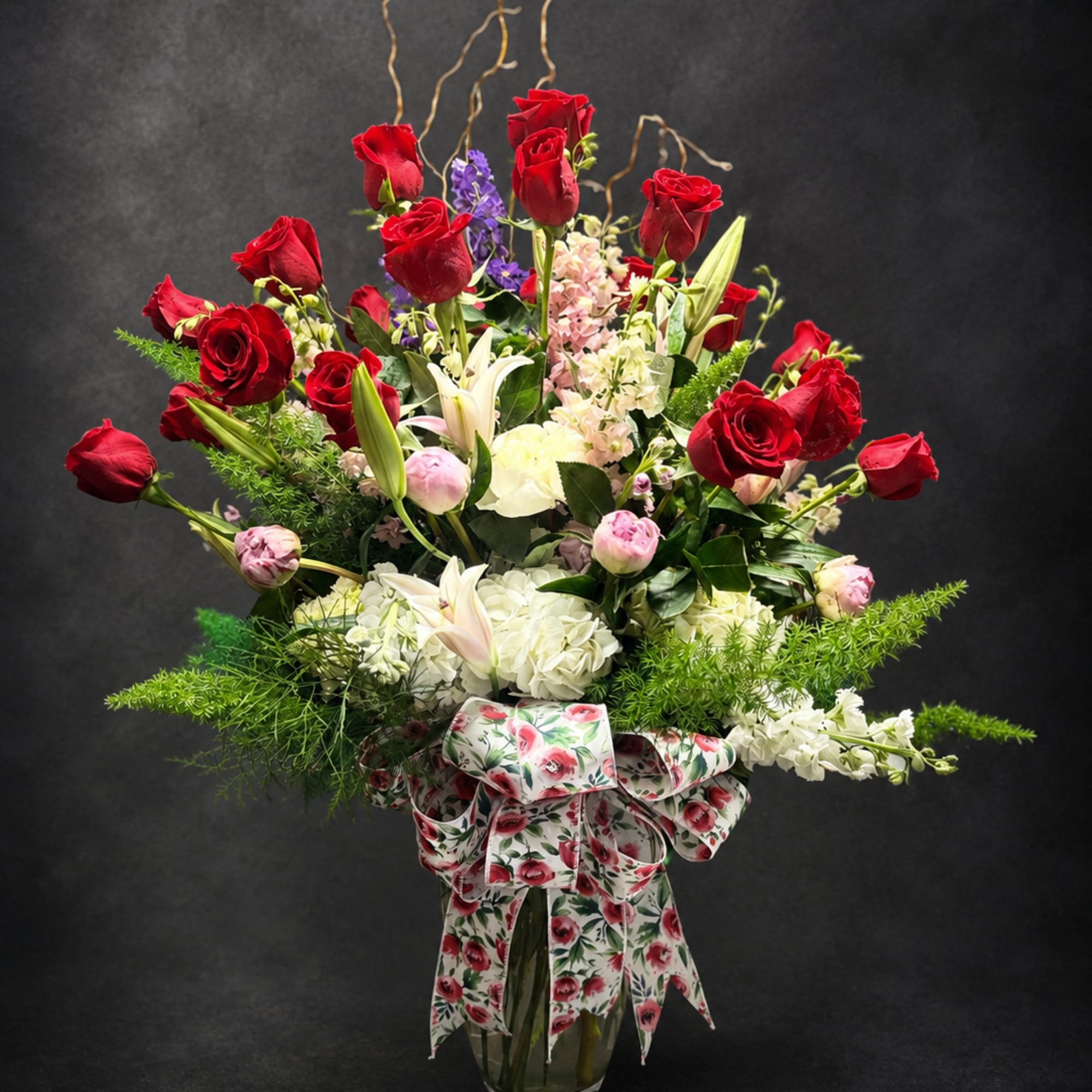 Bright red roses rising above white lilies and soft pink blooms give