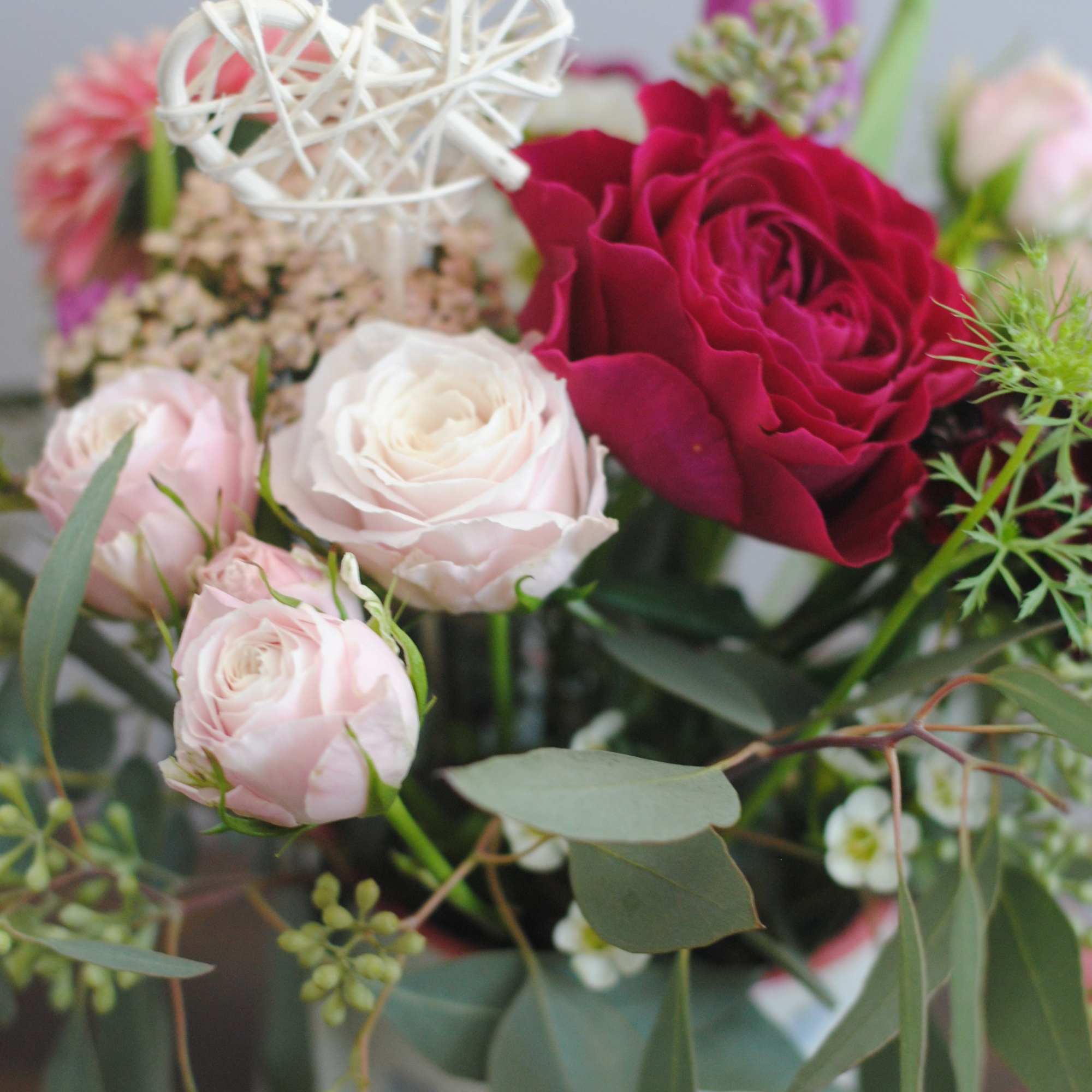 Bouquet of pink and red roses with a white decorative heart pick