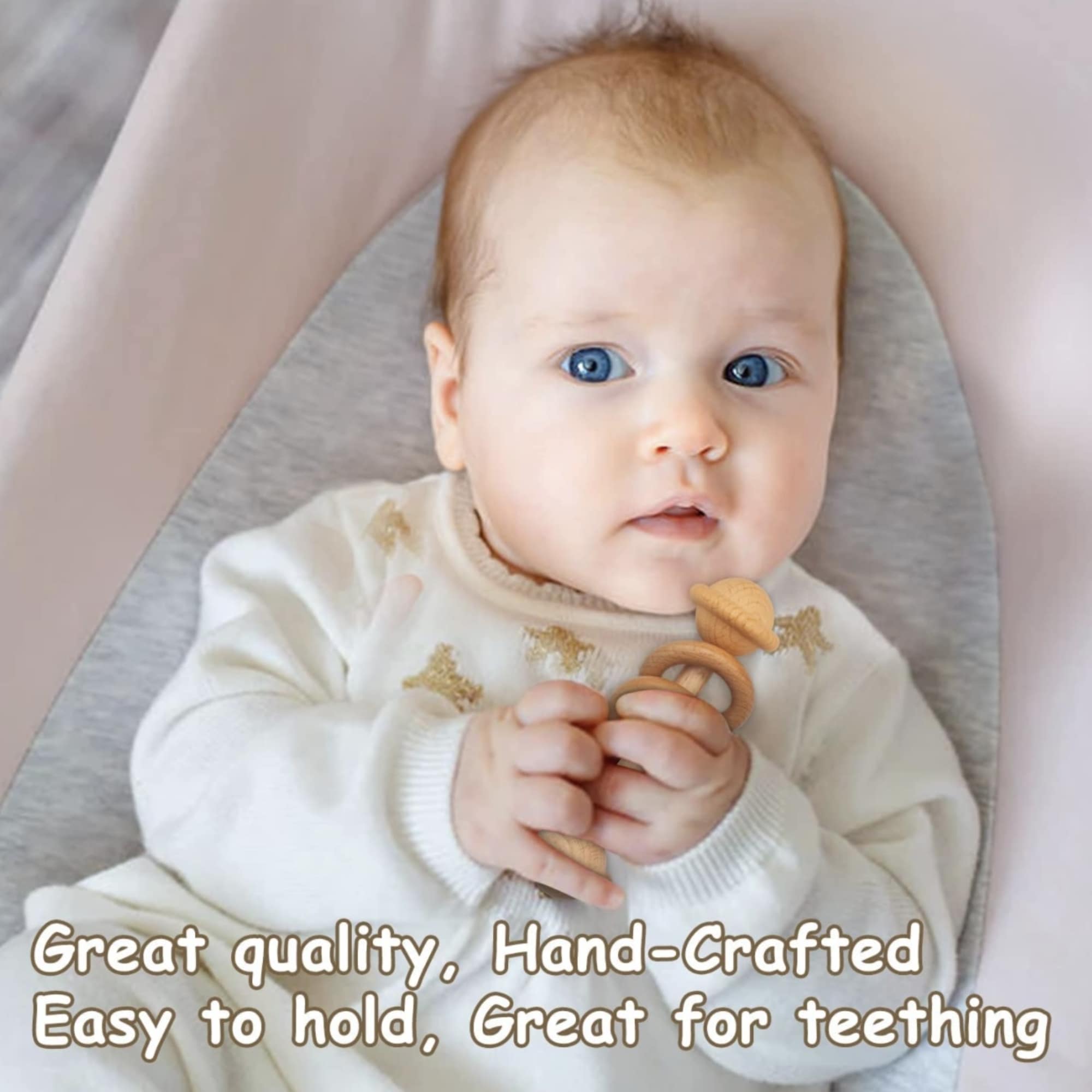 Baby holding a wooden teething toy on a soft blanket