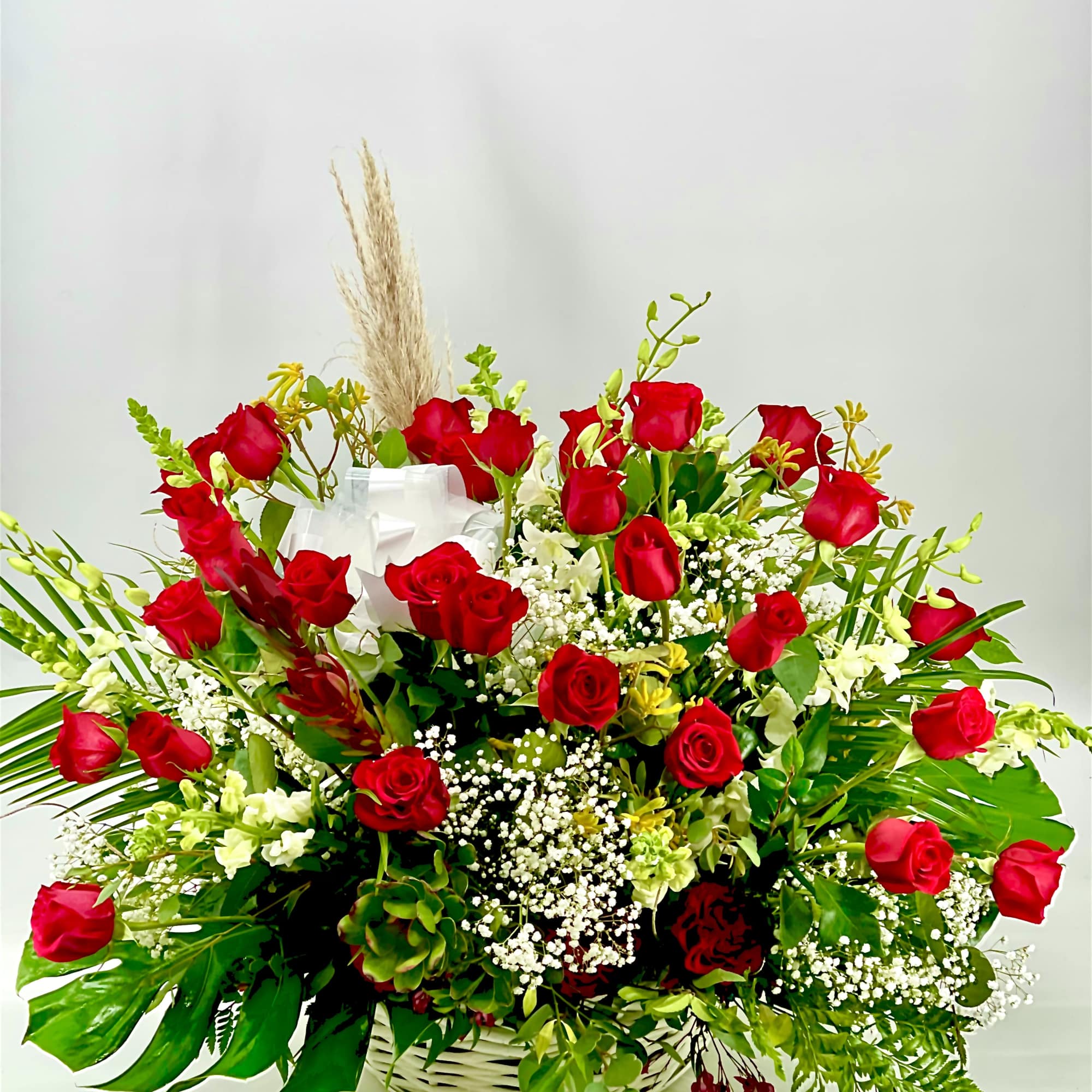 Basket arrangement of red roses with white filler flowers and greenery