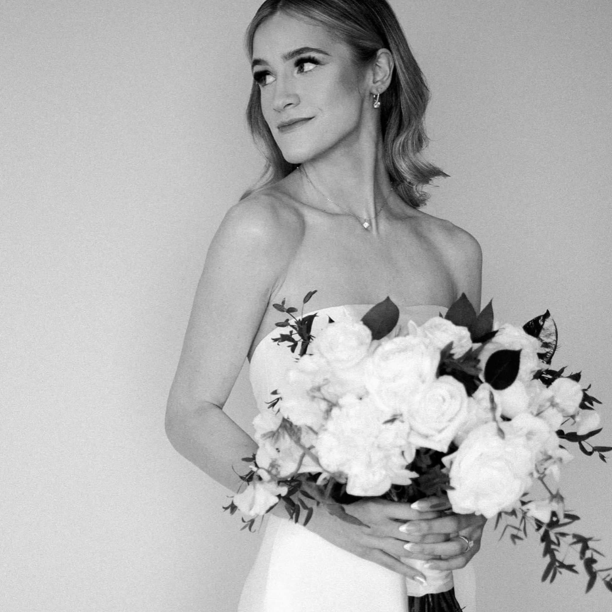 Bride holding a white bouquet with dark foliage