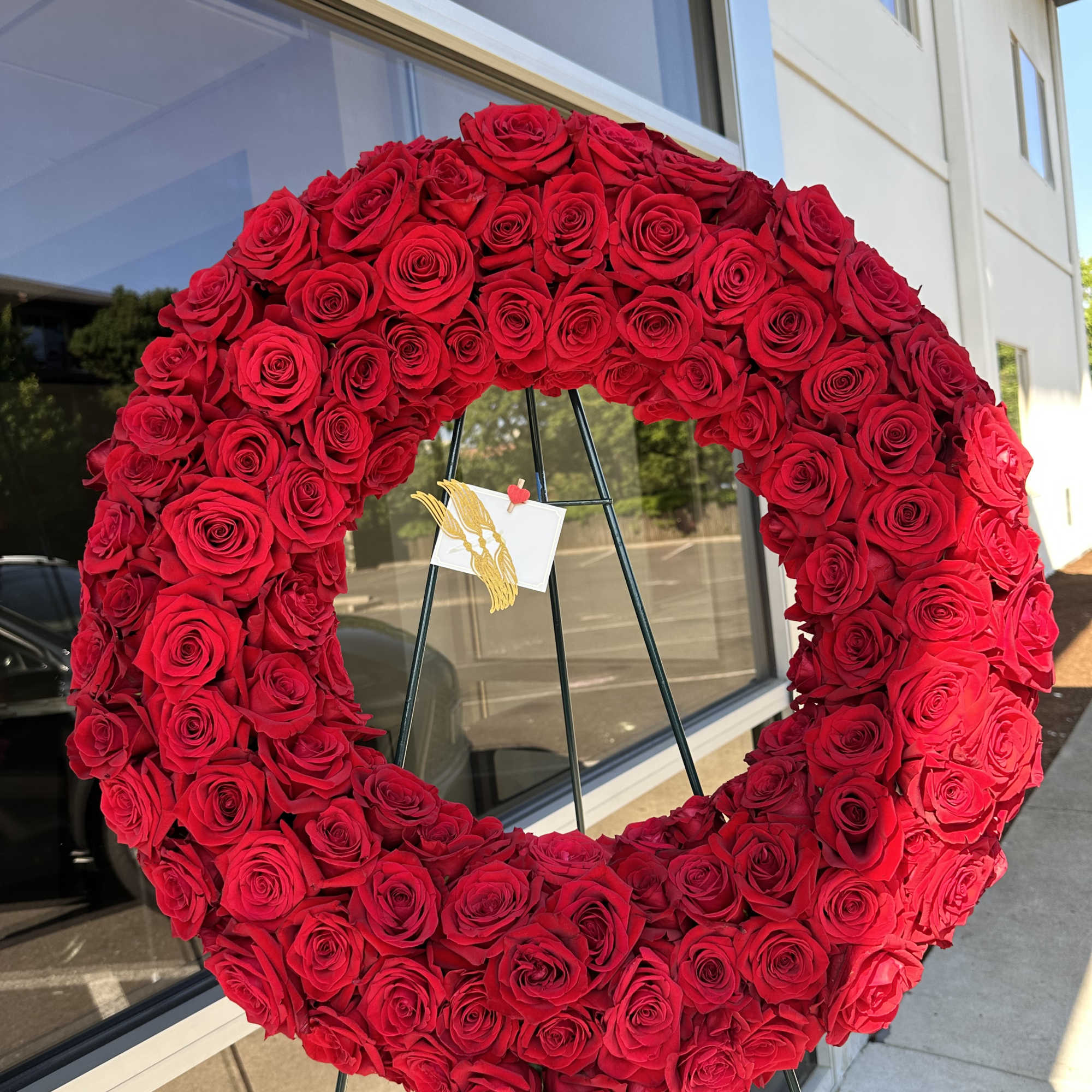 A full, circular sympathy wreath centered on creamy white roses creates an