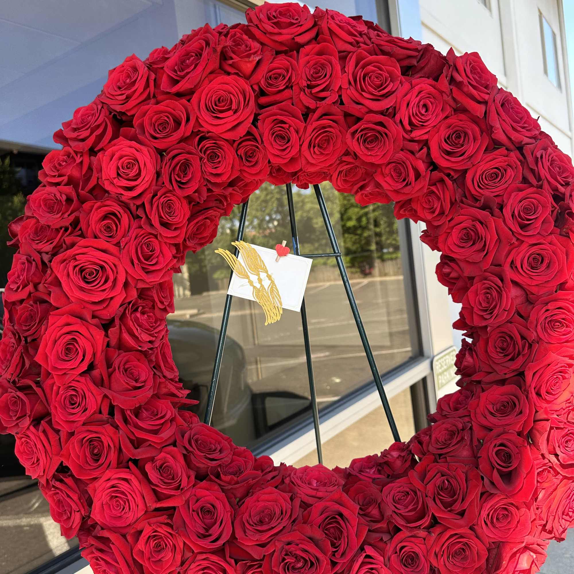 A full, circular sympathy wreath centered on creamy white roses creates an