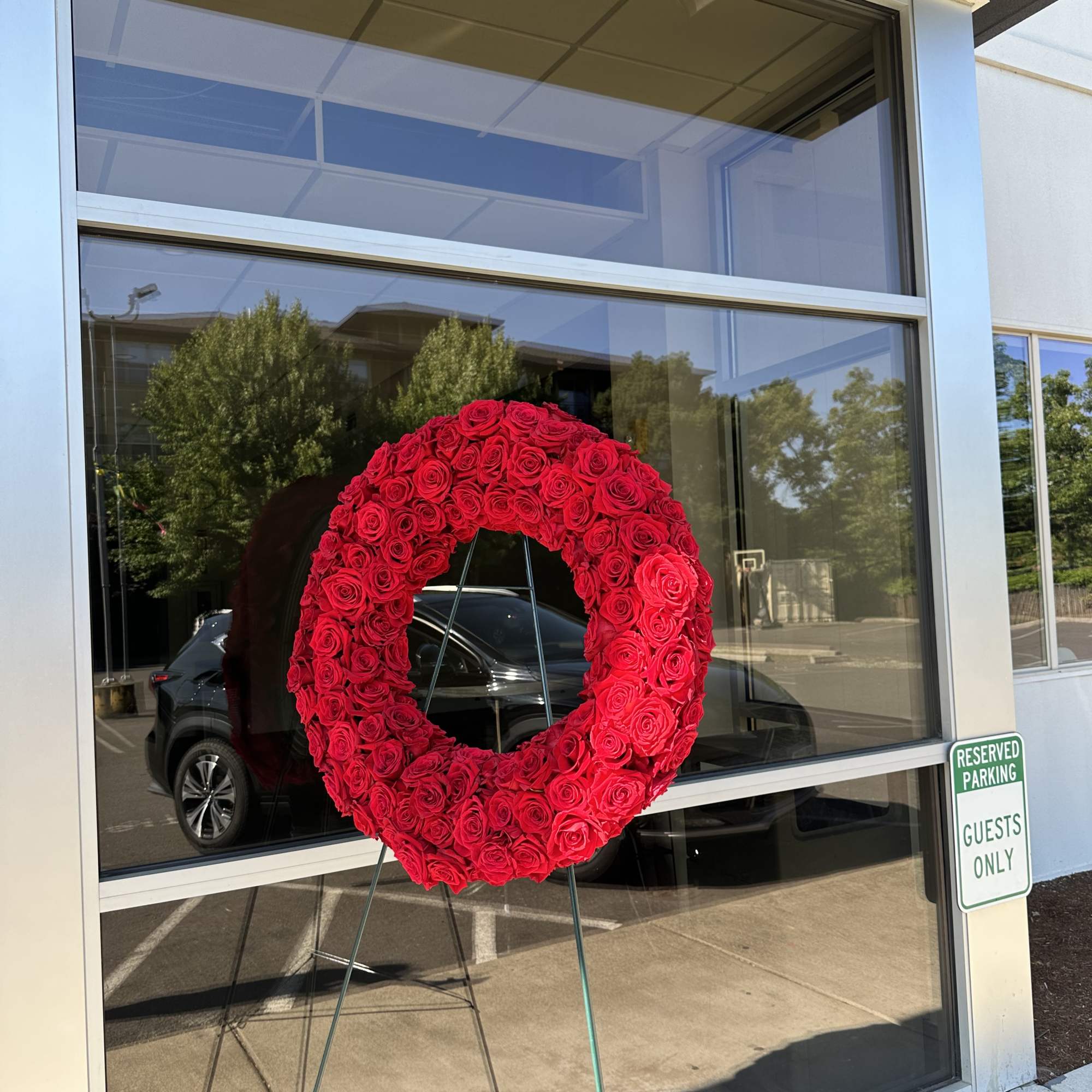A full, circular sympathy wreath centered on creamy white roses creates an