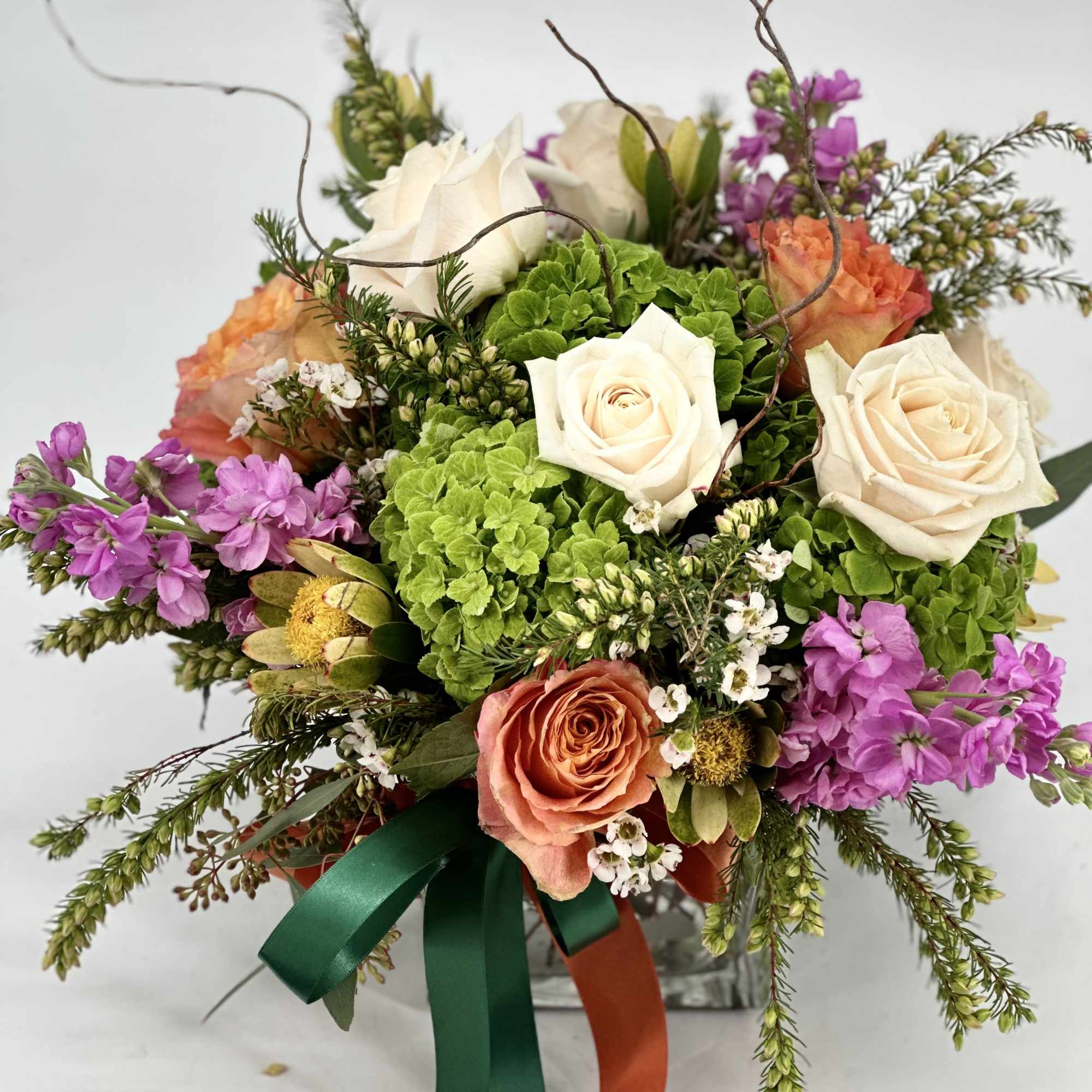 This arrangement includes blush pink roses, red roses, blush spray roses, white