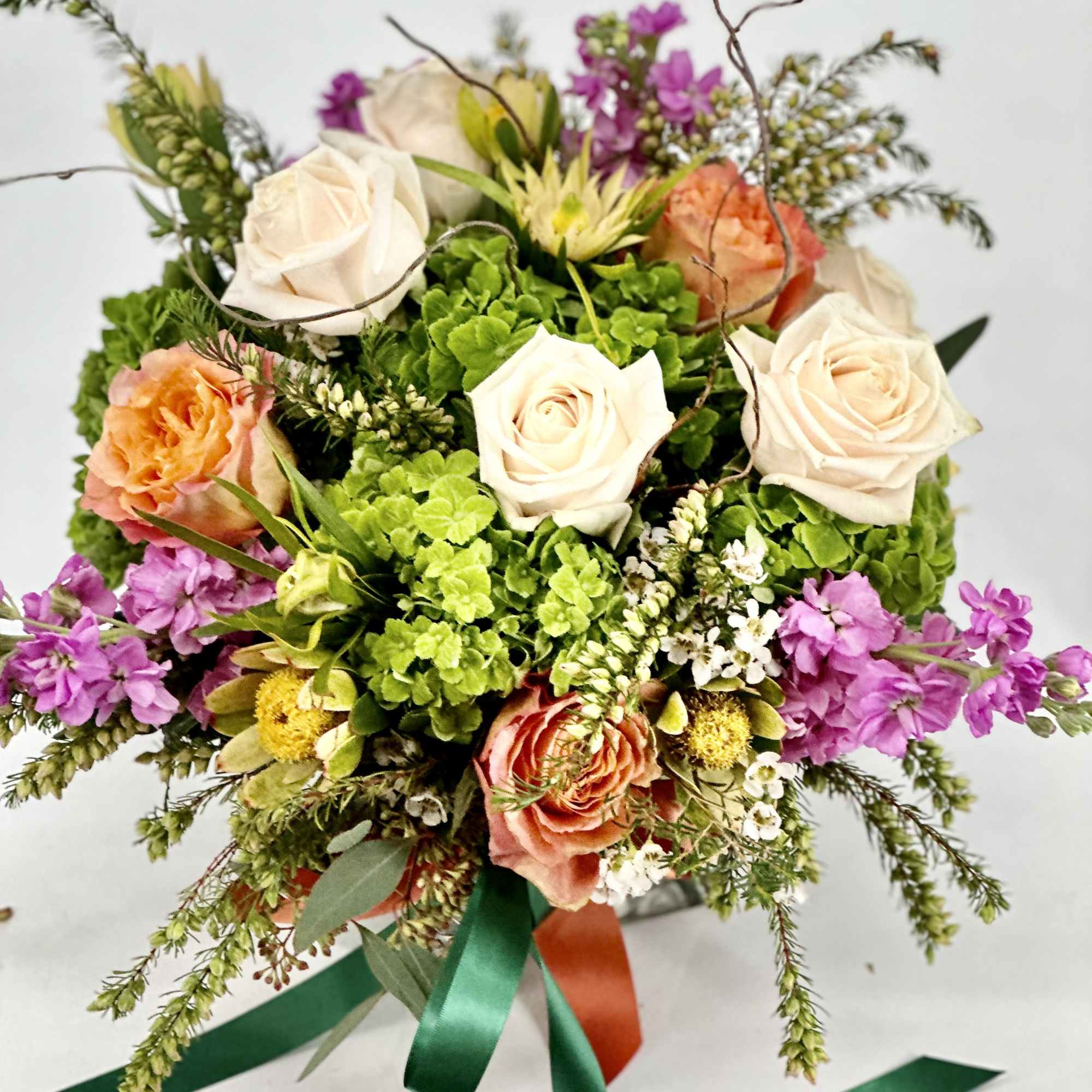 This arrangement includes blush pink roses, red roses, blush spray roses, white