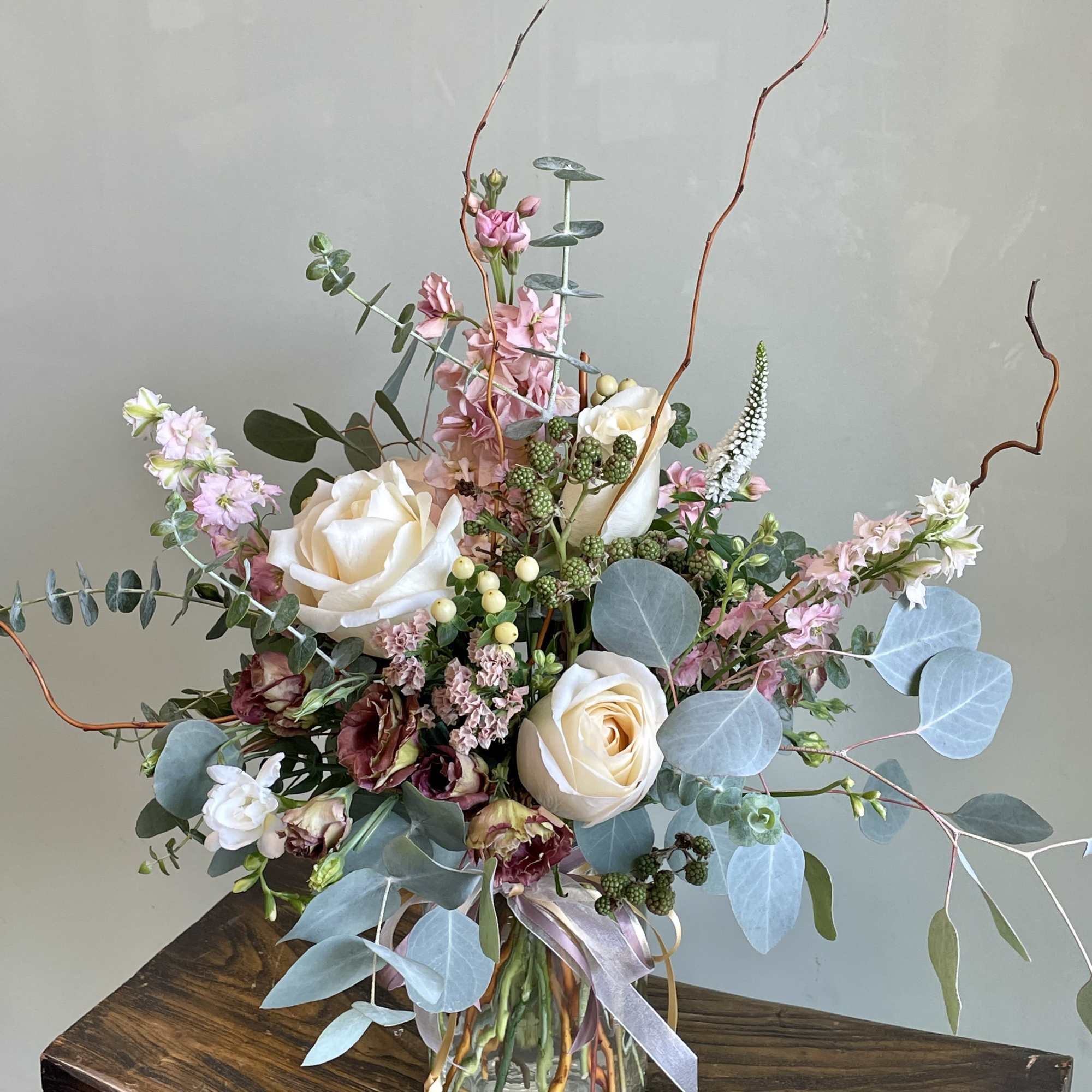 Tall bouquet of cream roses and pink flowers in a glass vase