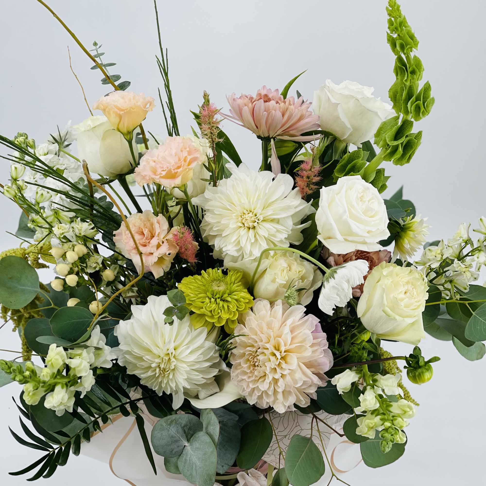Mixed bouquet of white, blush, and green flowers in wrapping paper