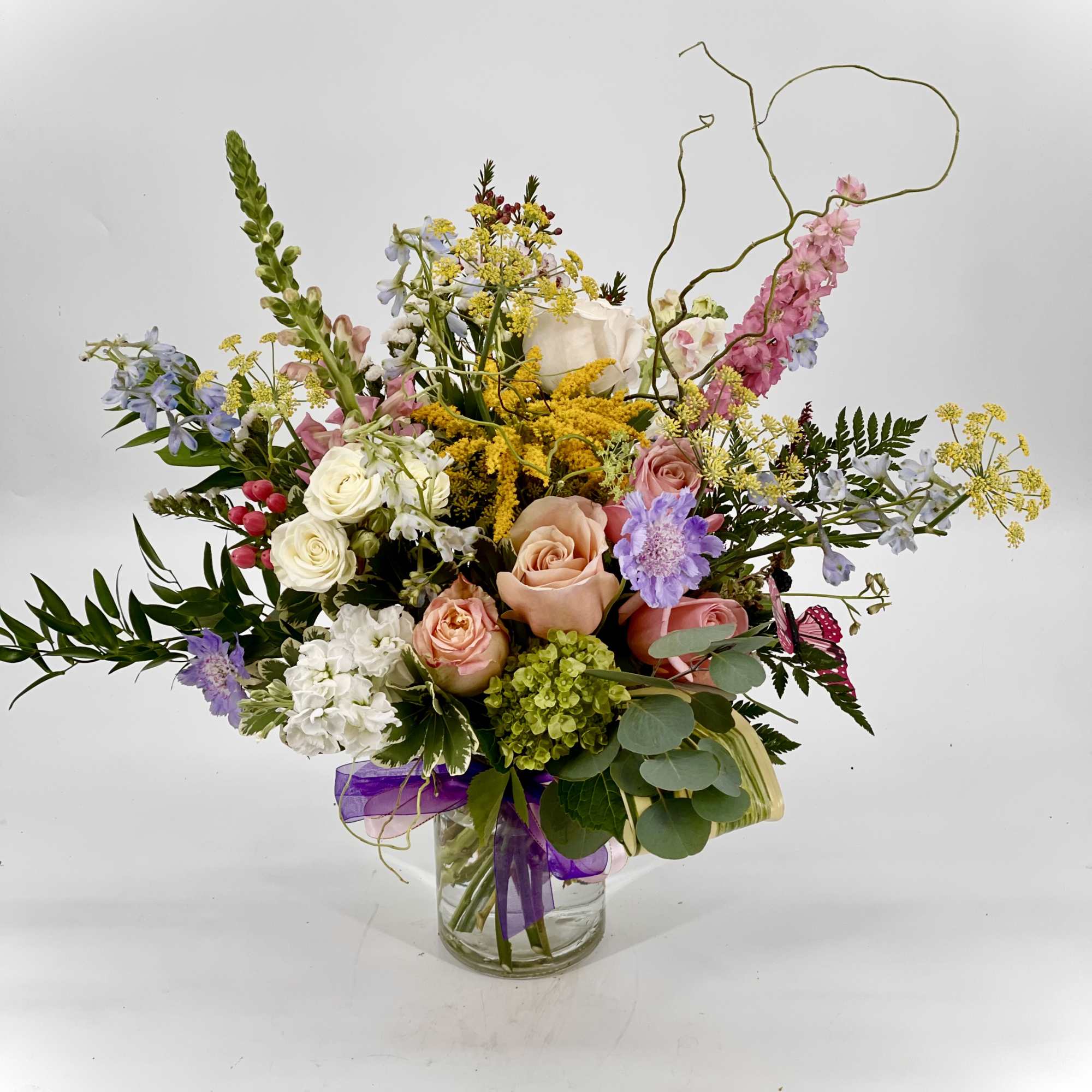 Mixed bouquet of pastel roses and wildflowers in a glass vase