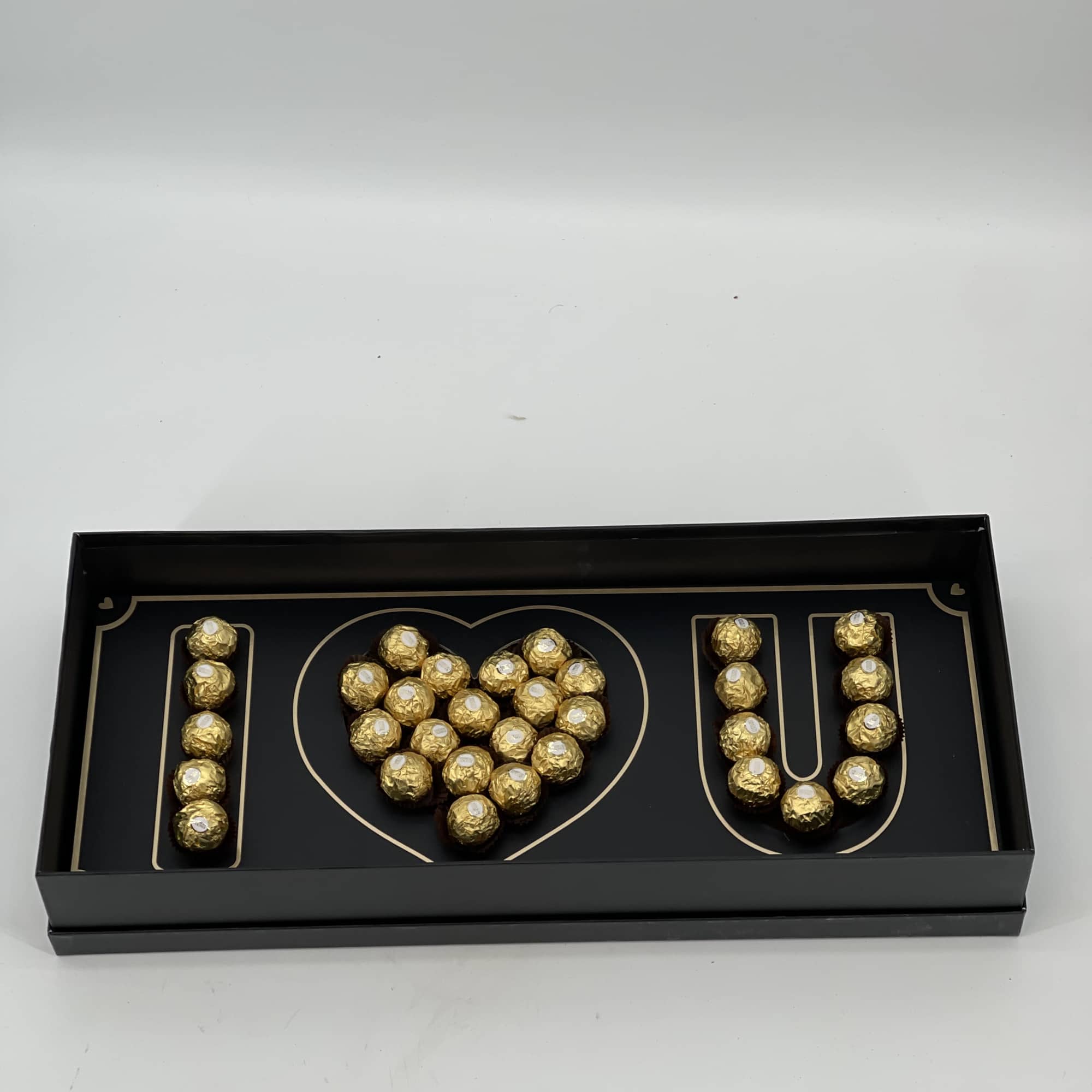 Black gift box with gold foil letters filled with chocolates
