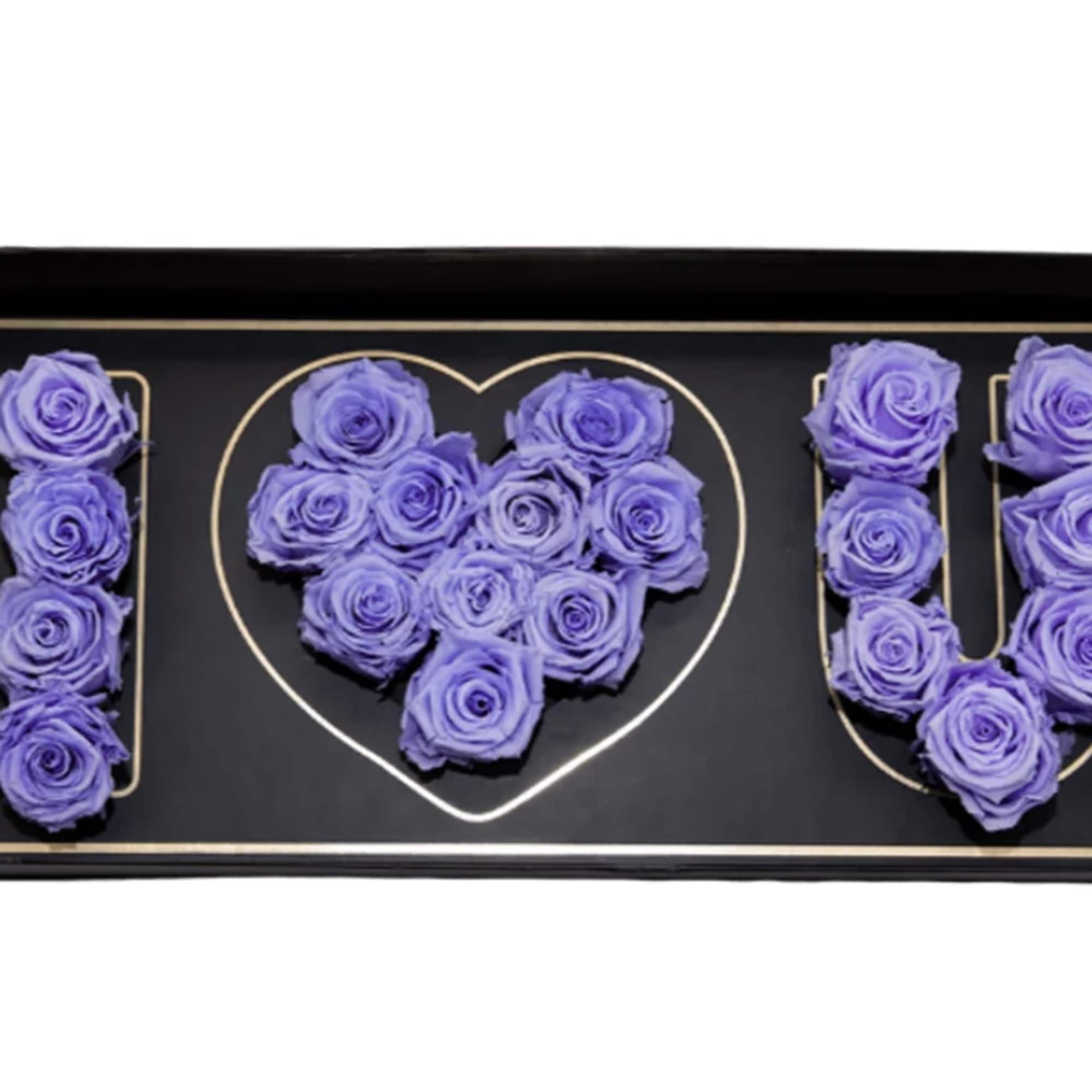 Purple roses arranged to spell I love you in a black tray