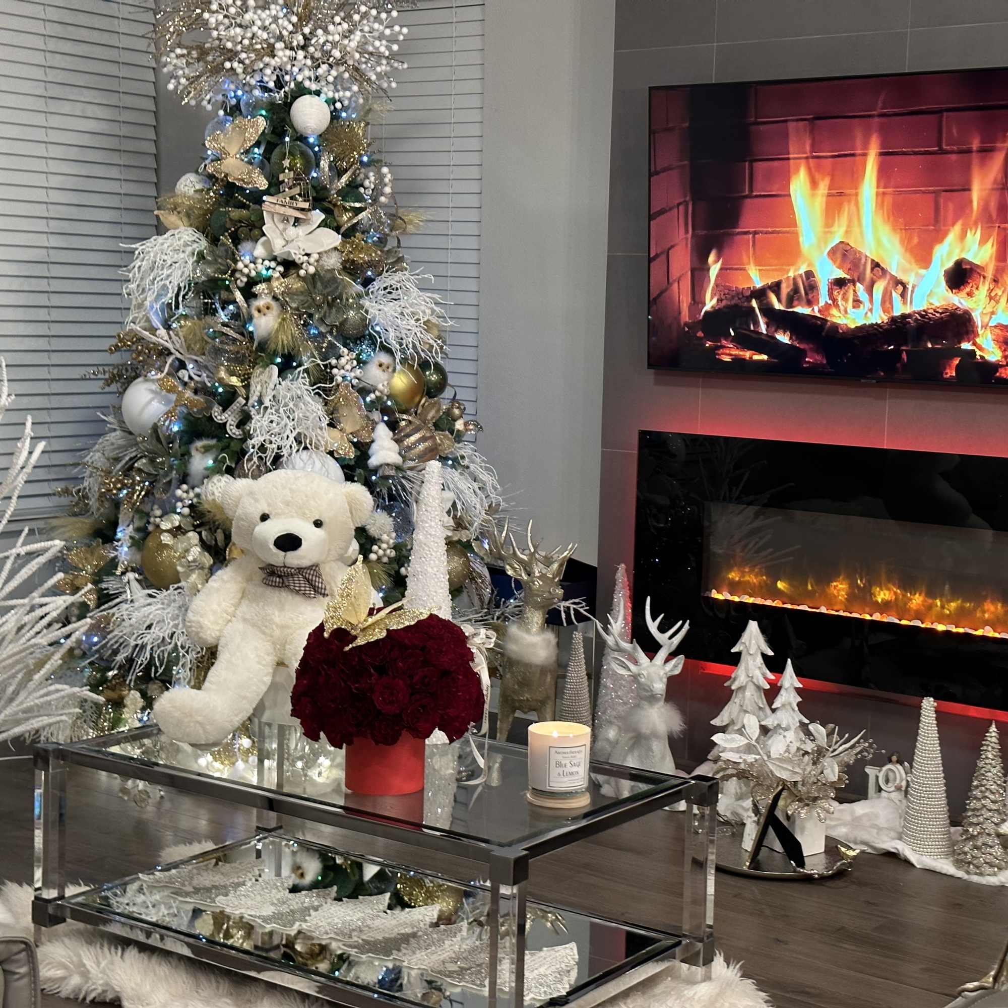 Decorated Christmas tree with a teddy bear and a red flower arrangement in a living room