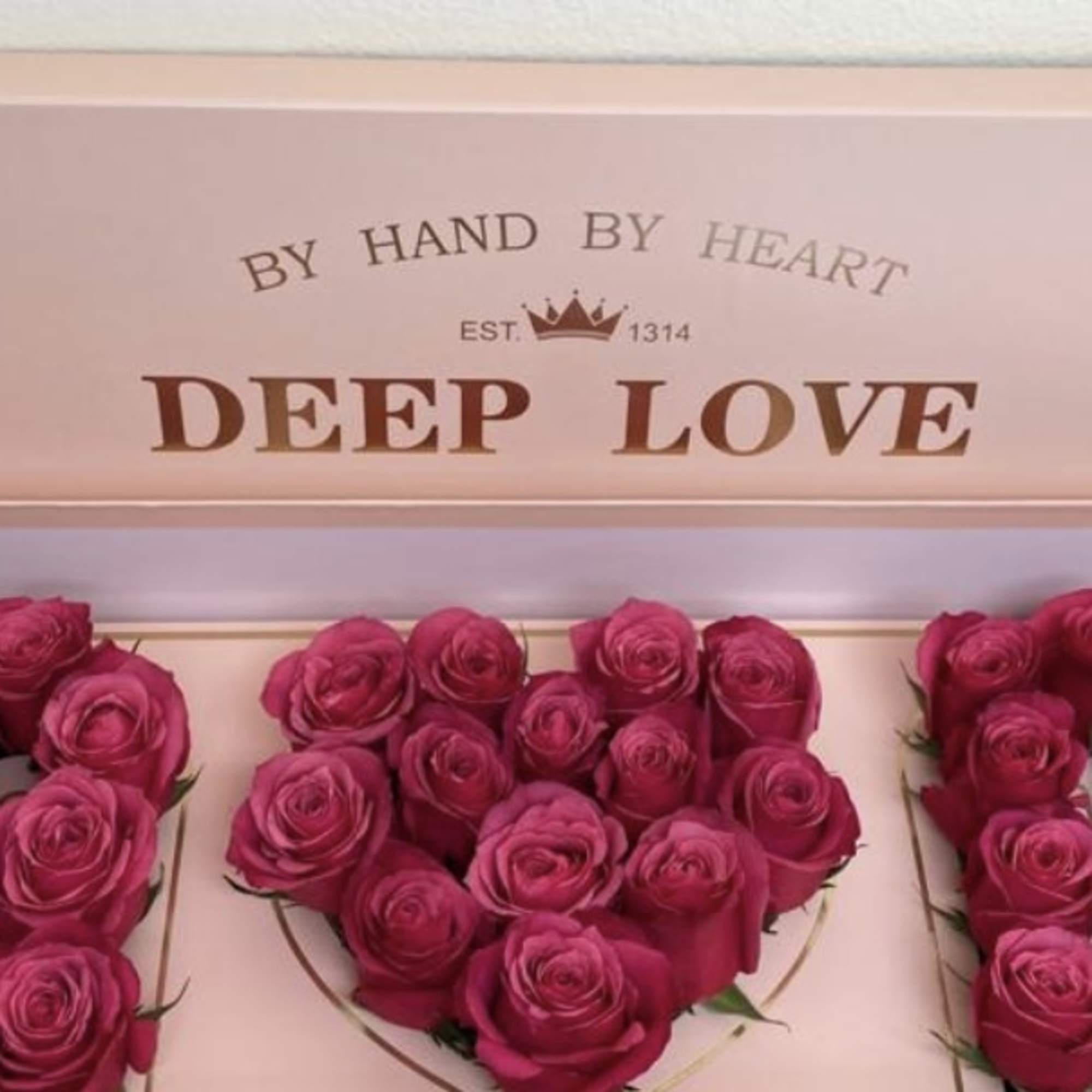 Pink roses arranged in a gift box spelling "LOVE"