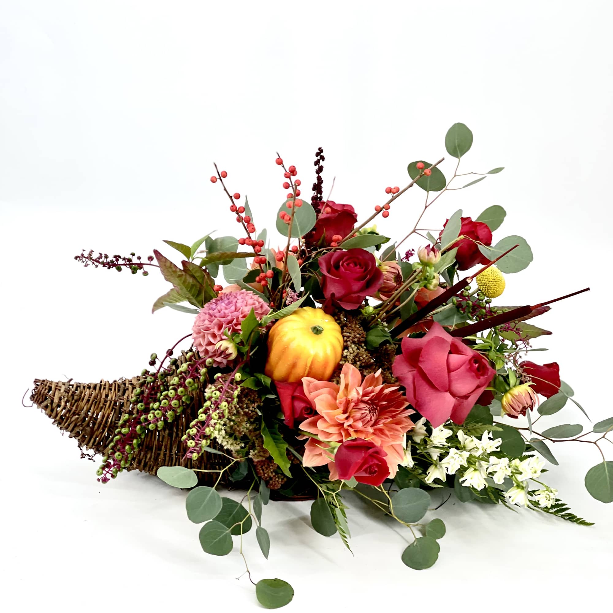 Low floral arrangement with red and pink blooms in a wicker basket