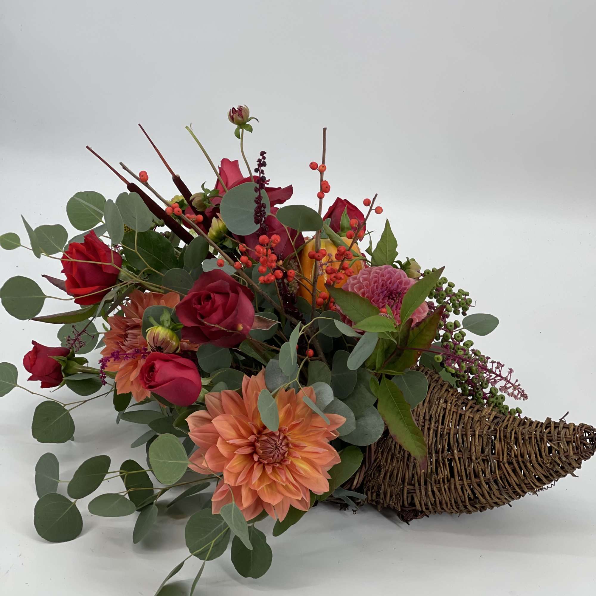 Mixed bouquet with red roses and peach dahlias in a wicker basket