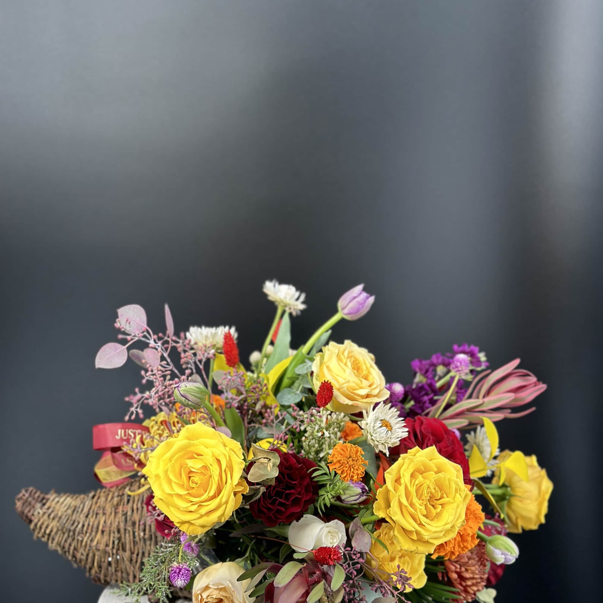 Mixed bouquet with yellow and red roses in a low container