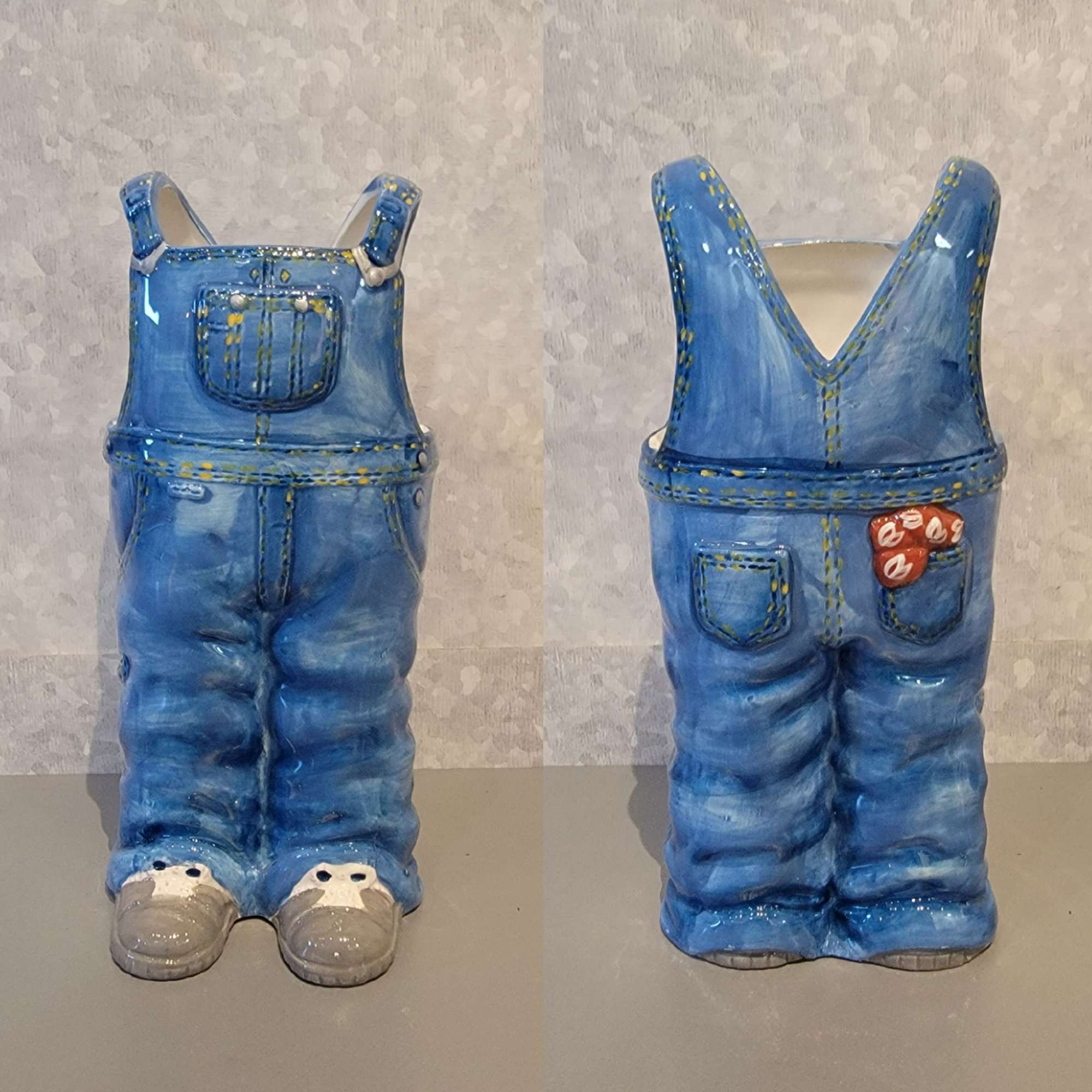 Two blue ceramic vases shaped like overalls with pockets and shoes.