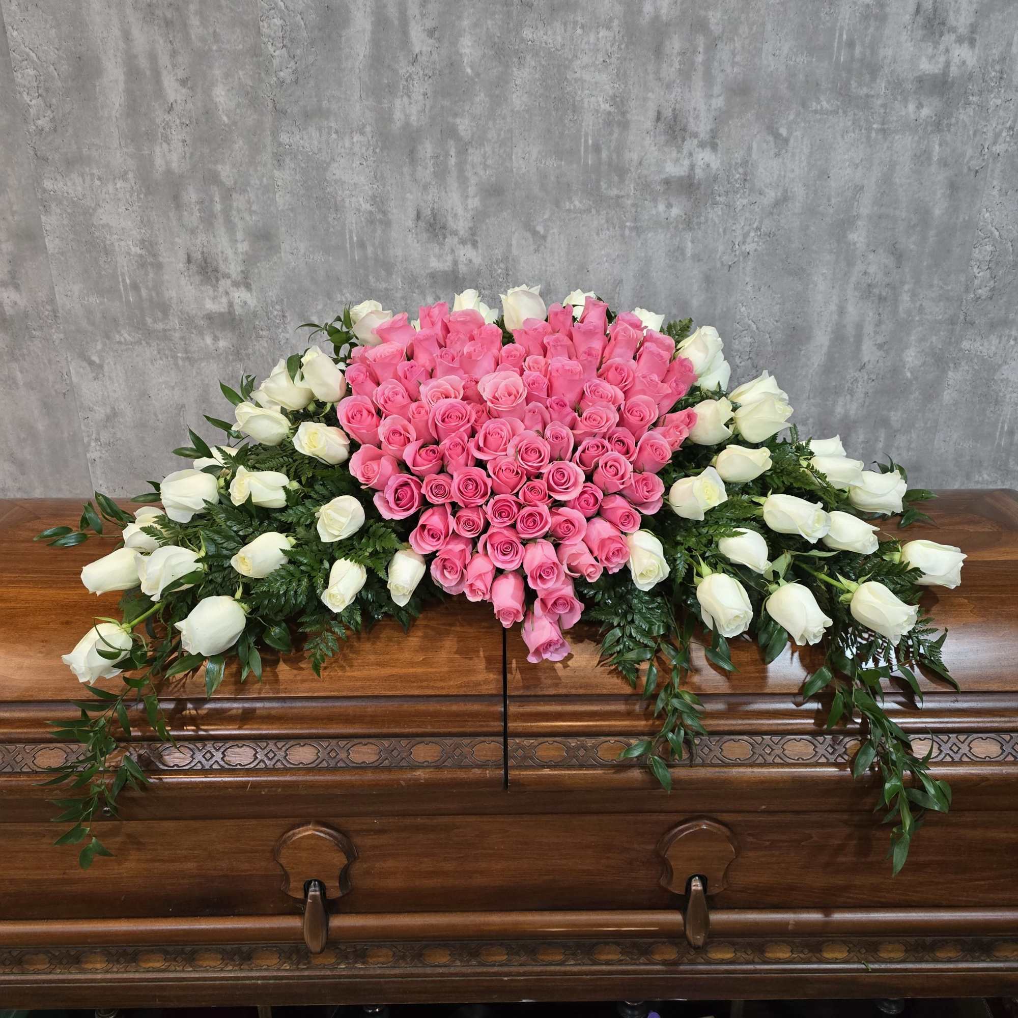 Pink and white rose arrangement on a wooden casket