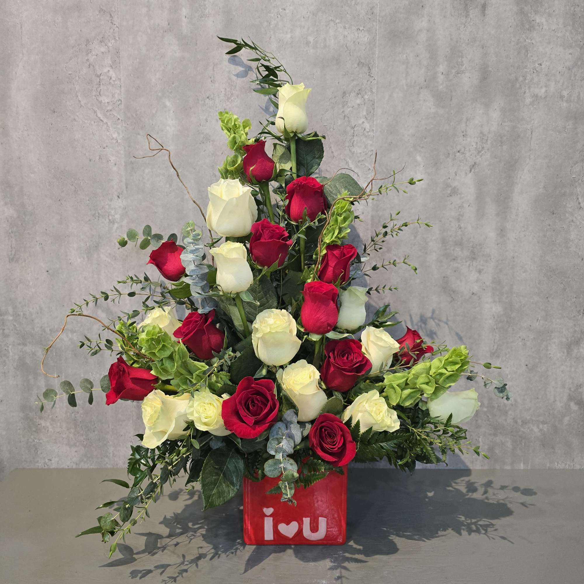 Red and white roses arranged in a red vase with an "I love you" design.