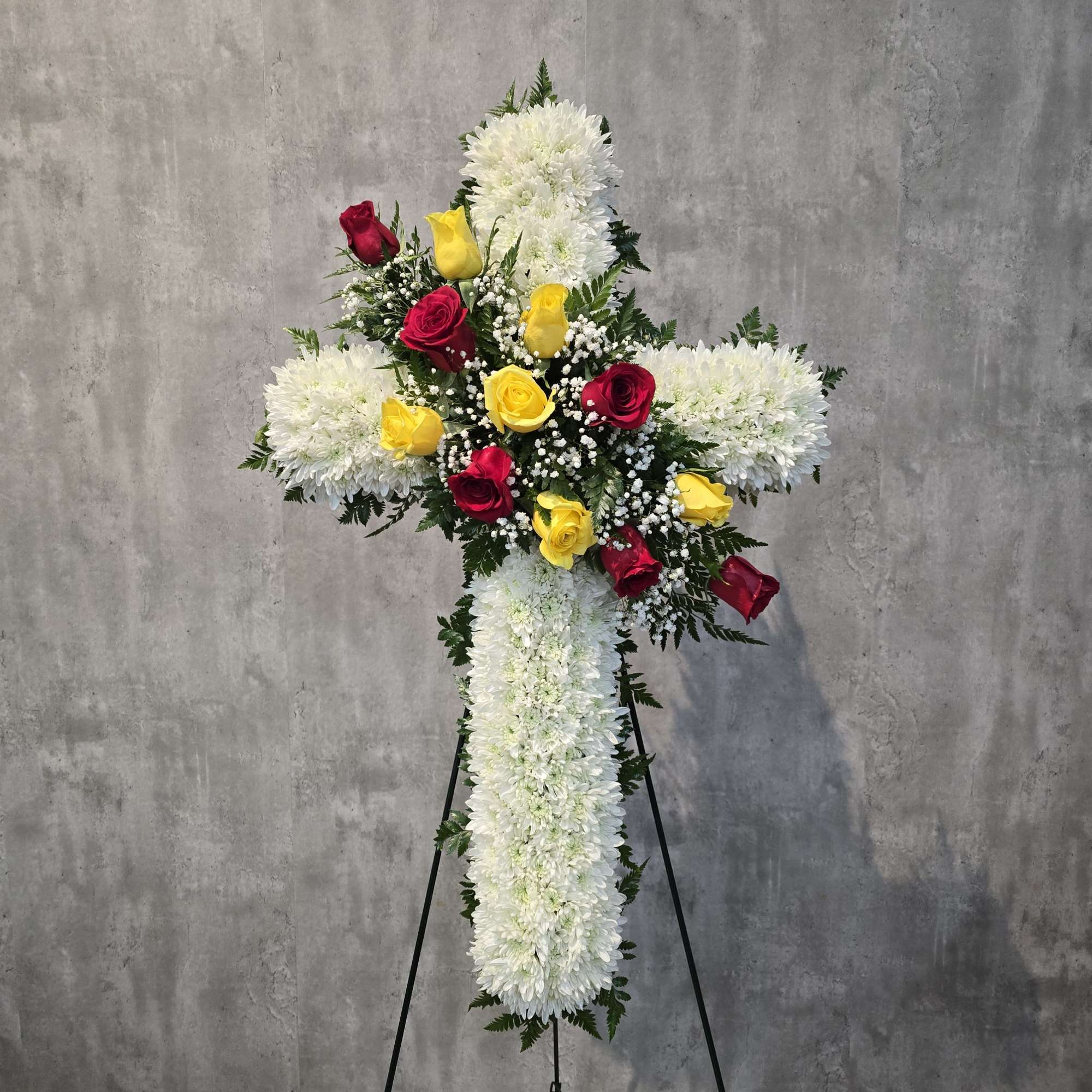 Standing floral cross with white chrysanthemums and red and yellow roses