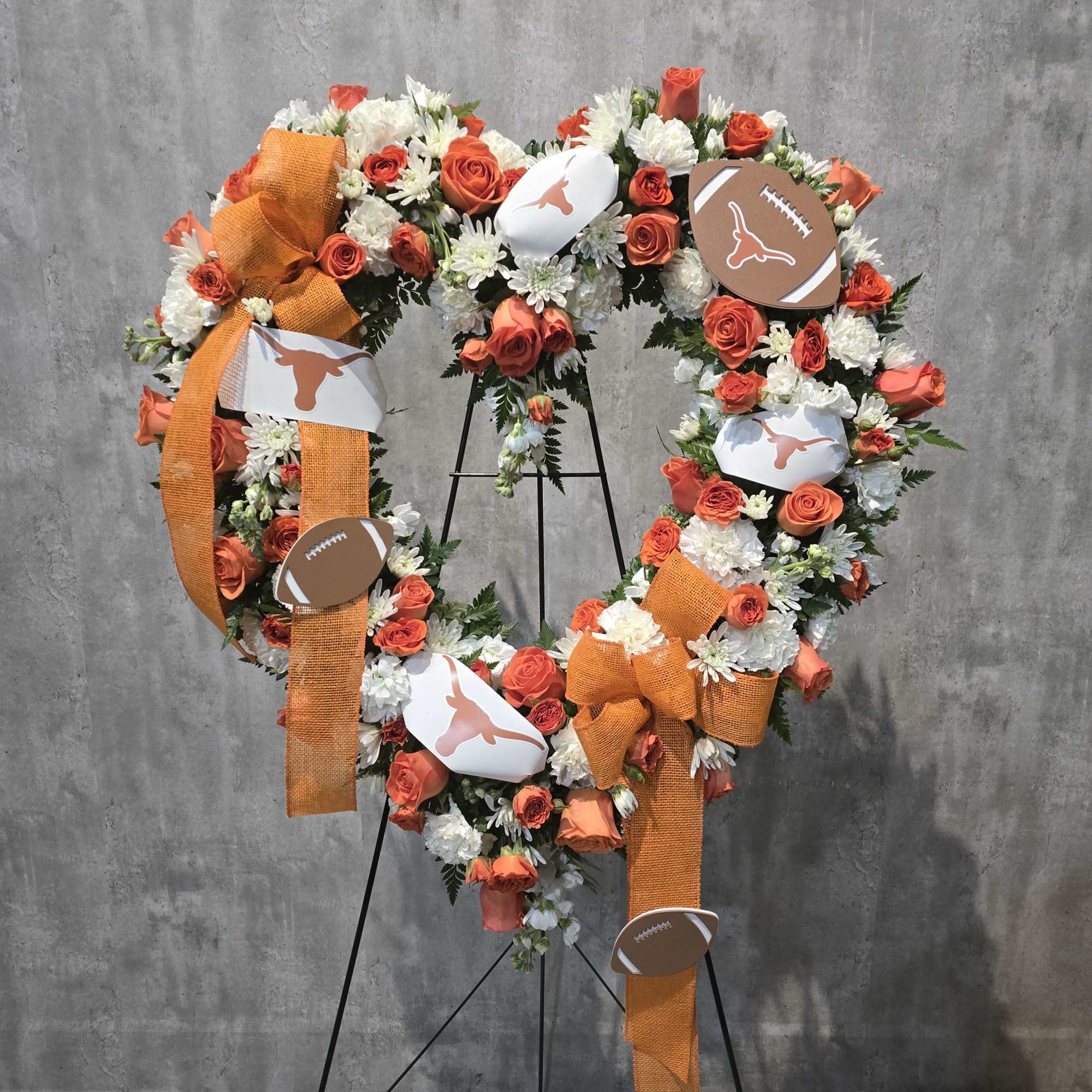 Football-themed floral wreath with orange and white flowers and ribbon