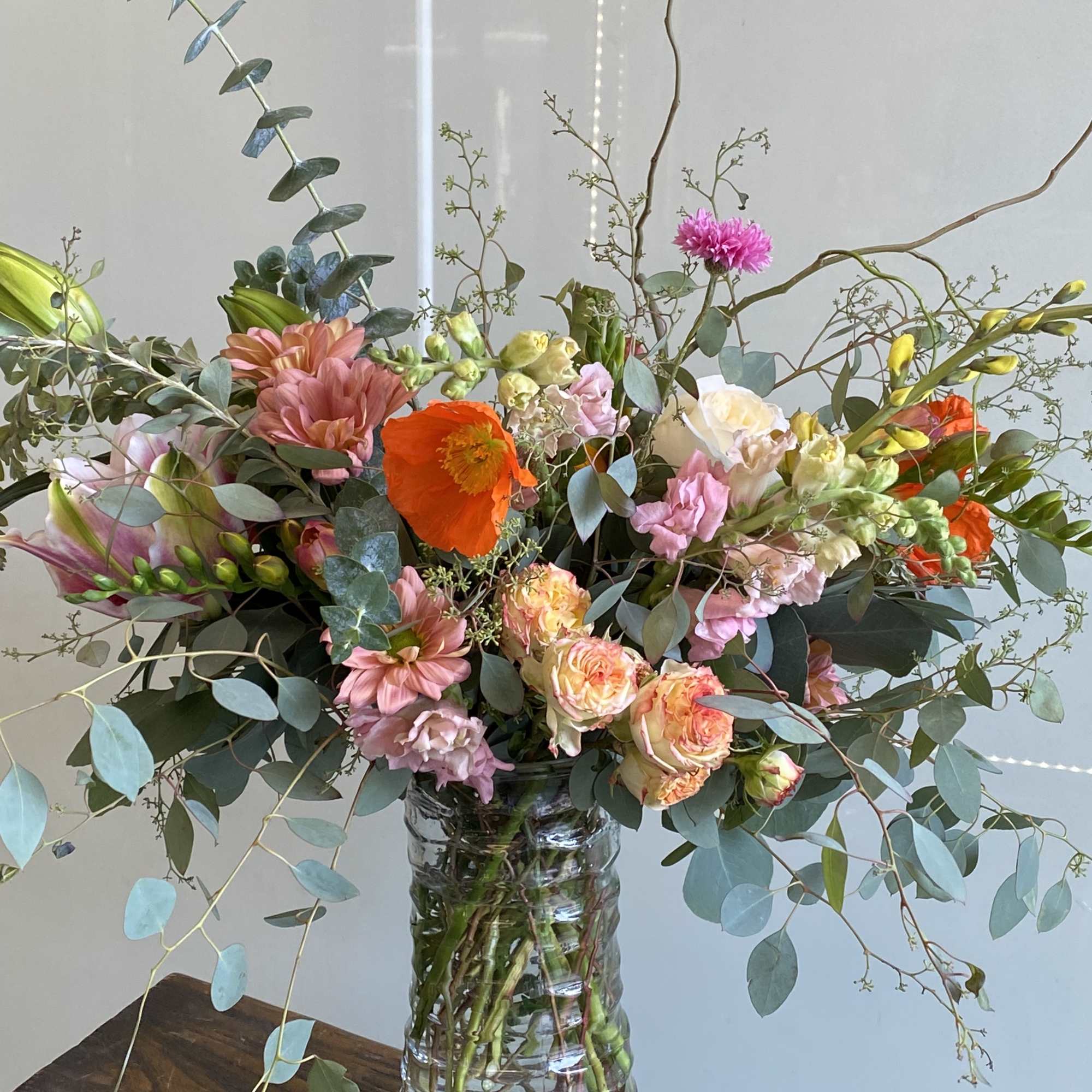 Mixed bouquet in a clear glass vase with pink, peach, and orange flowers
