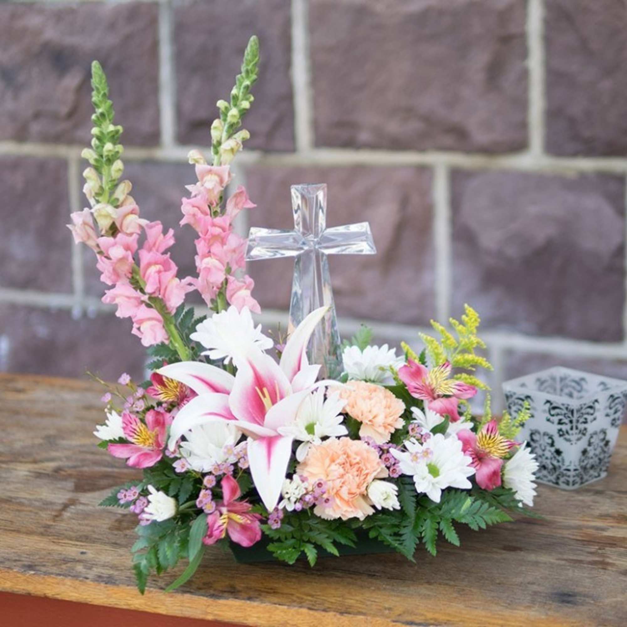 Pink and white floral arrangement with a clear glass cross centerpiece