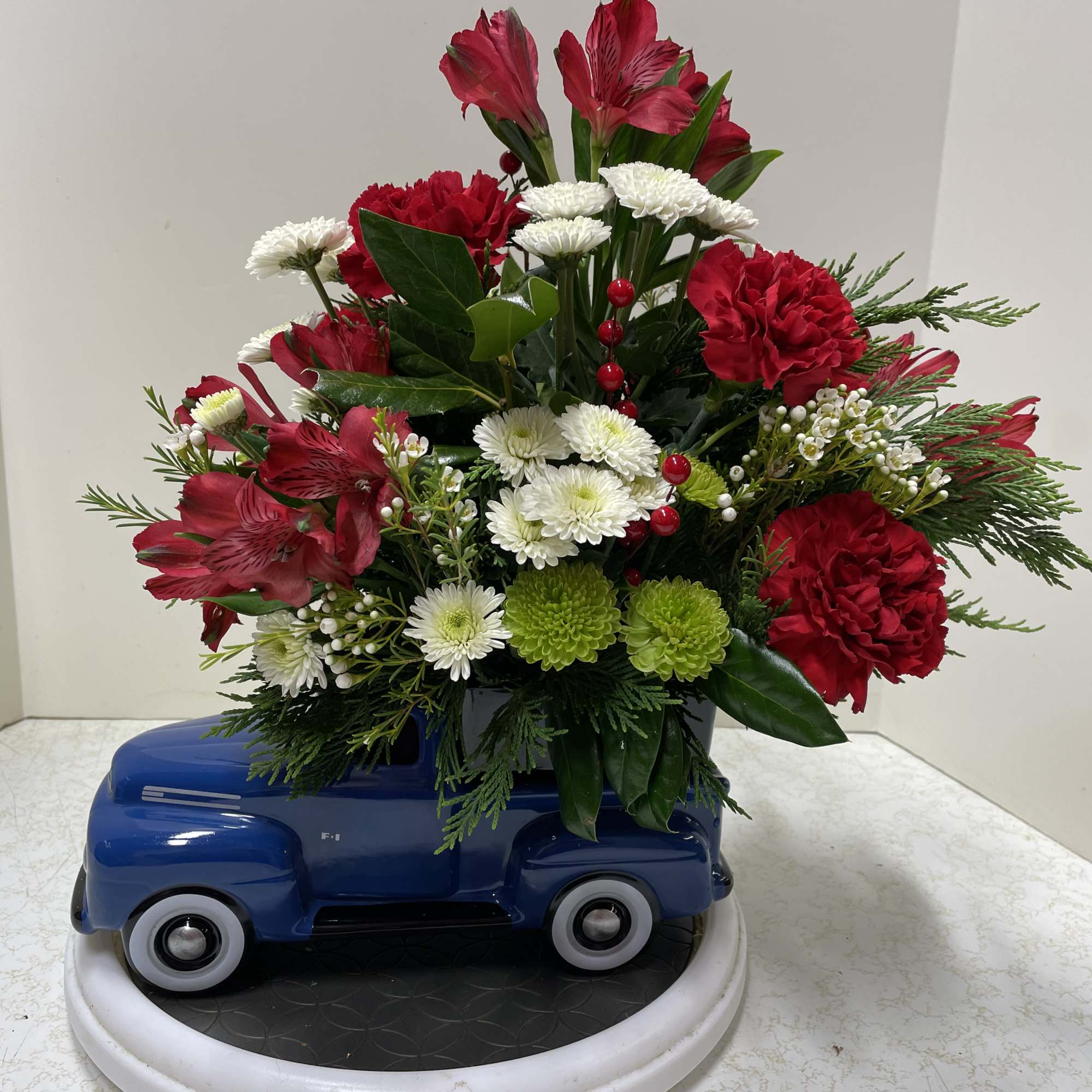 Red and white floral arrangement in a blue truck container