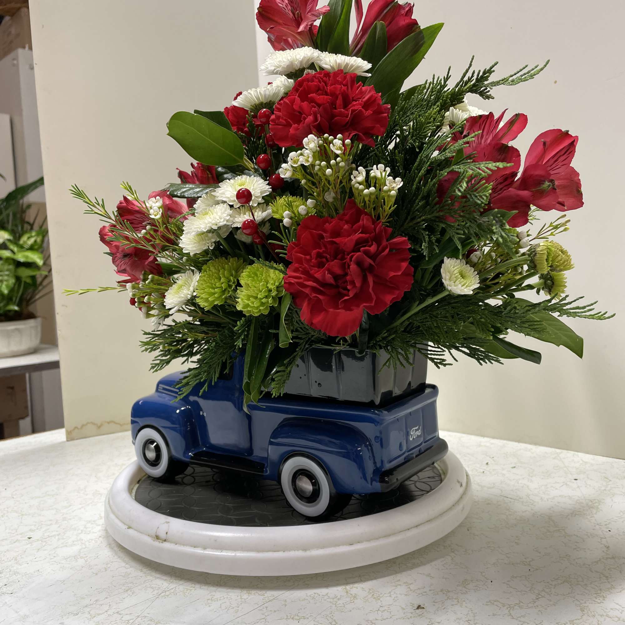 Red and white floral arrangement in a blue truck container