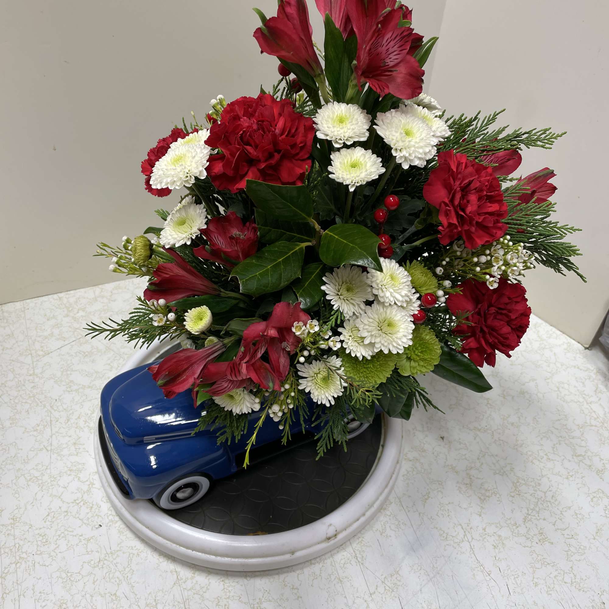 Red and white flower arrangement in a blue car-shaped container
