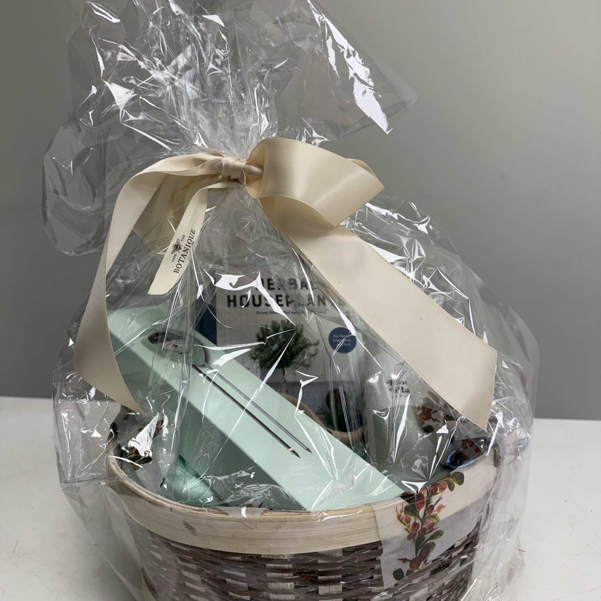 Gift basket wrapped in clear cellophane with a cream ribbon