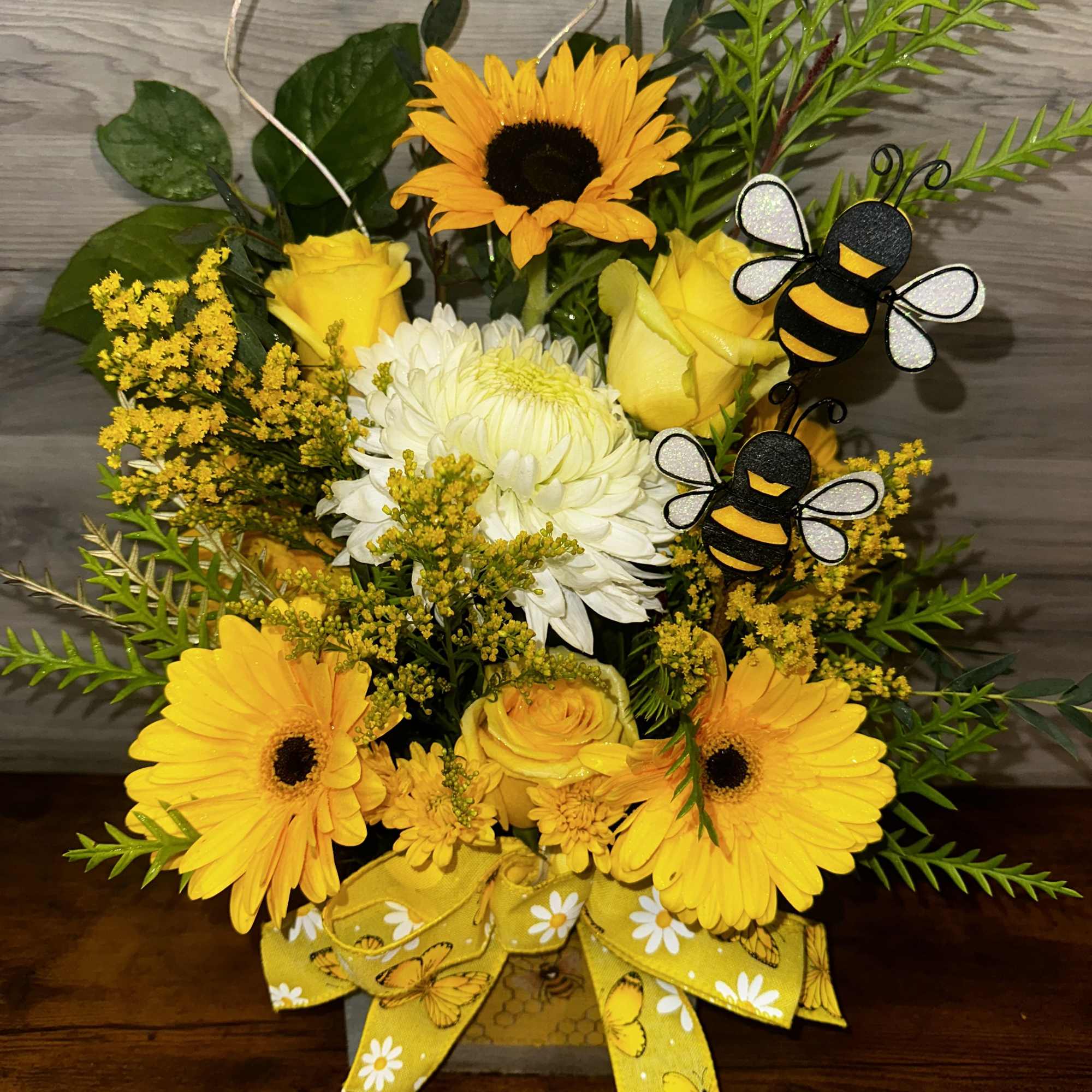 Yellow floral bouquet with bee decorations and a ribbon bow