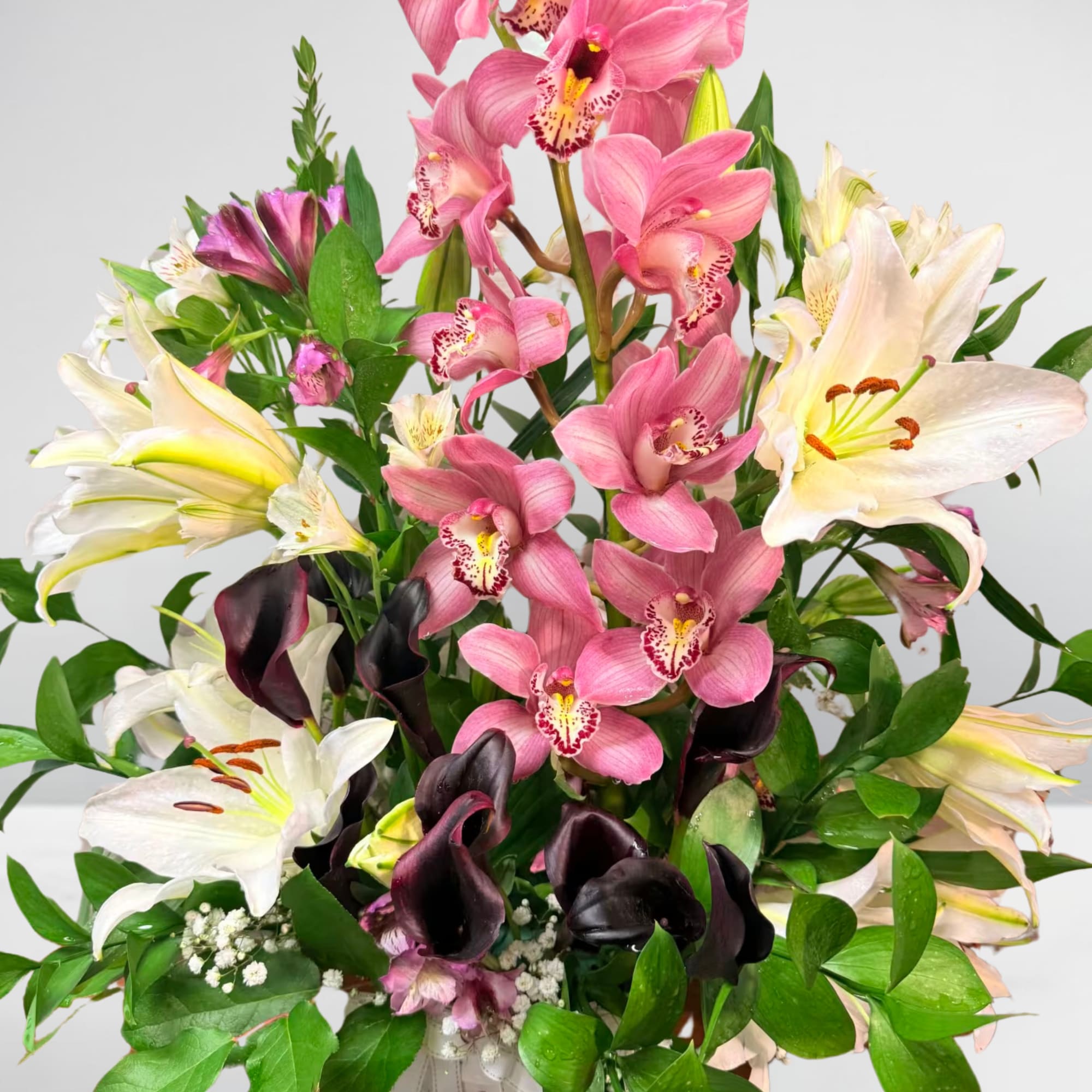 Bouquet of pink orchids, white lilies, and dark calla lilies