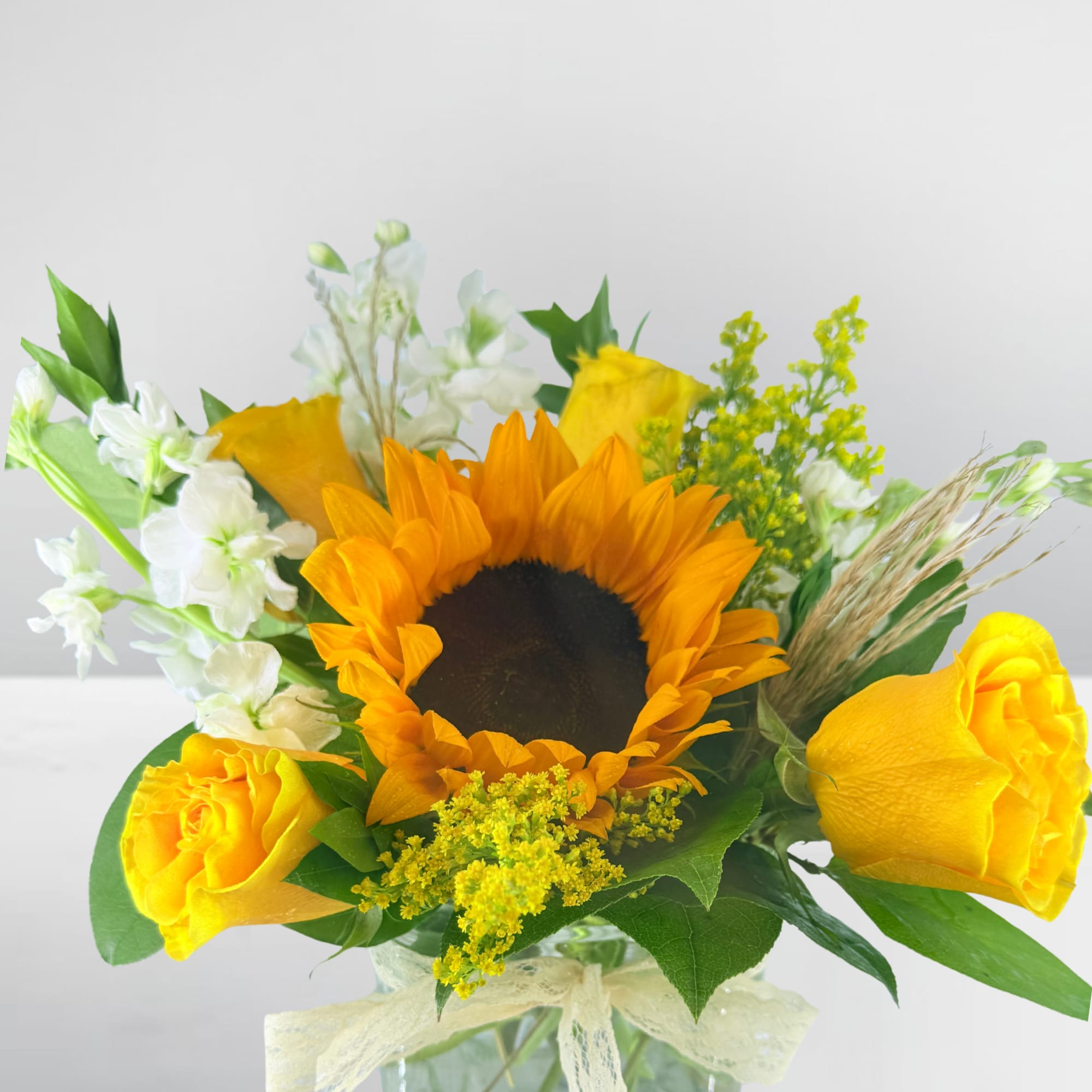 Sunflower and yellow rose bouquet in a glass vase