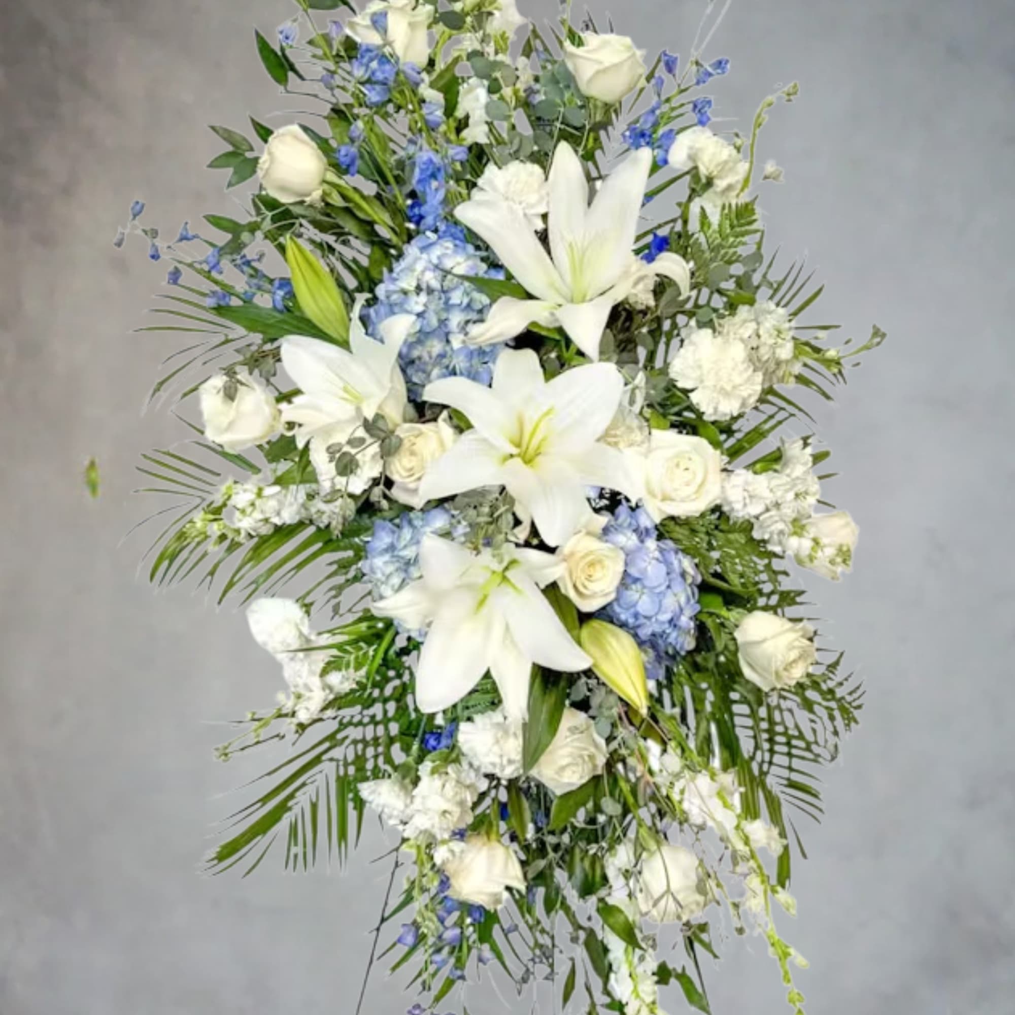 Tall white floral spray with lilies, roses, and blue accents, photo 2 of 2