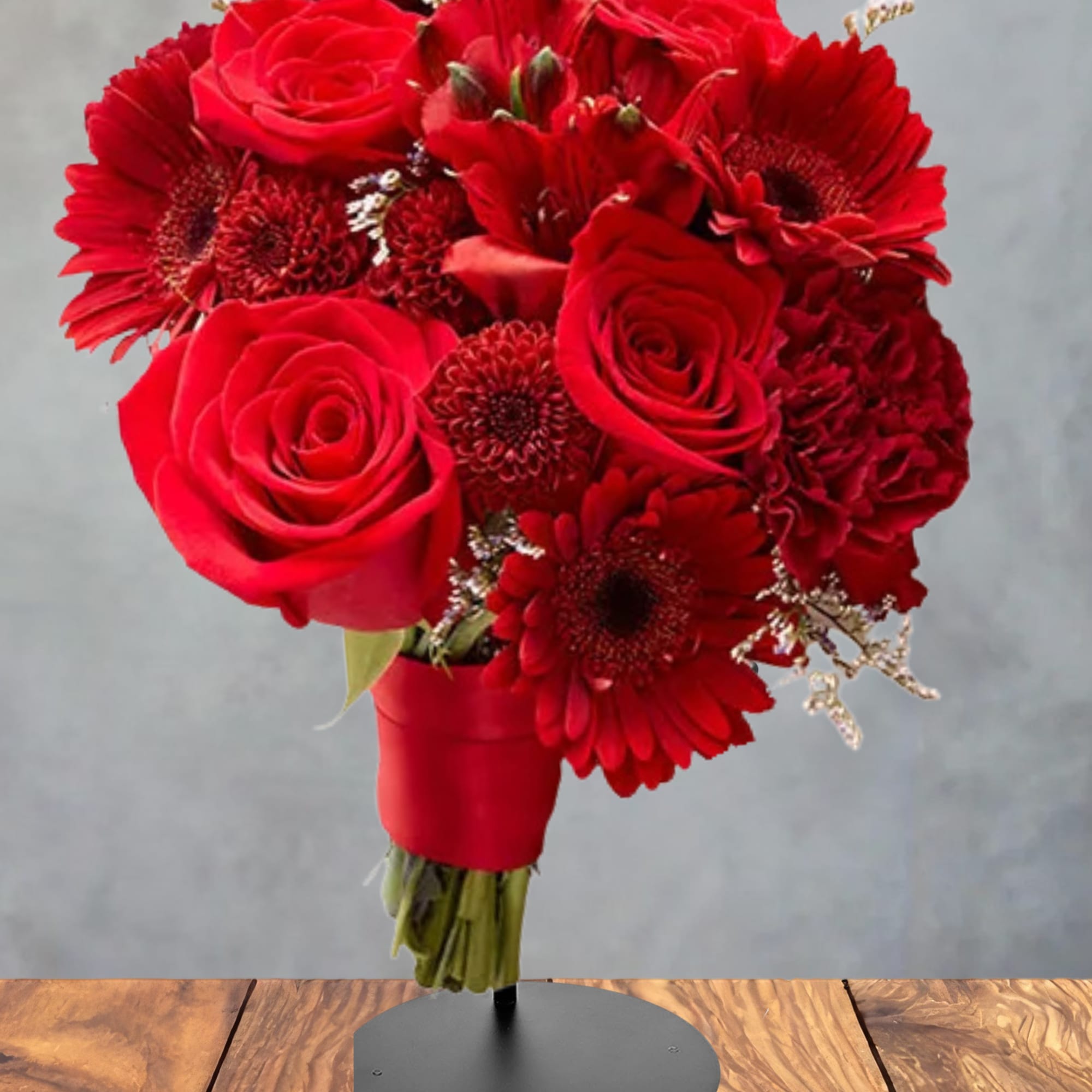 Red rose and gerbera daisy bouquet in a red wrap on a stand