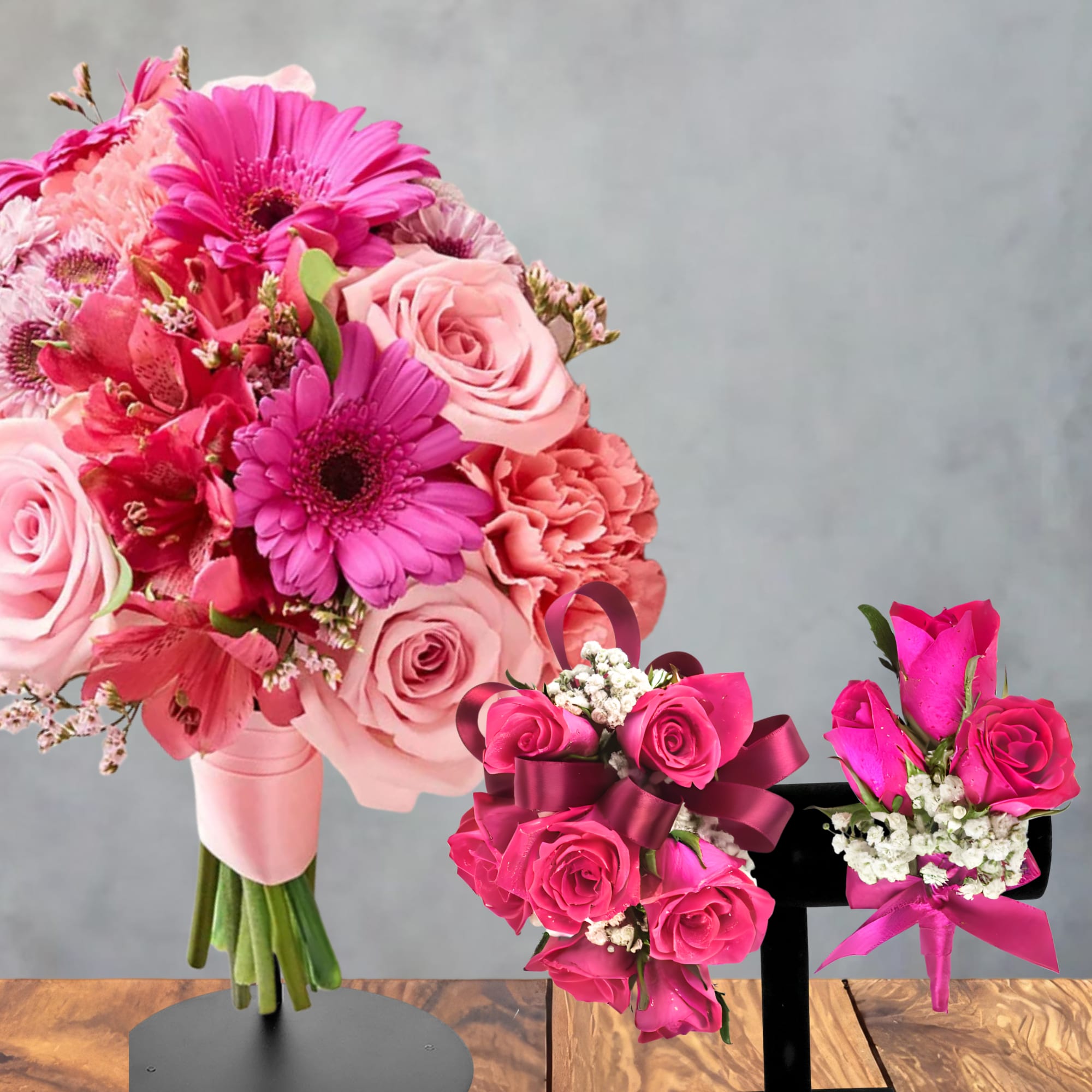 Three pink floral arrangements with roses and gerbera daisies on display stands