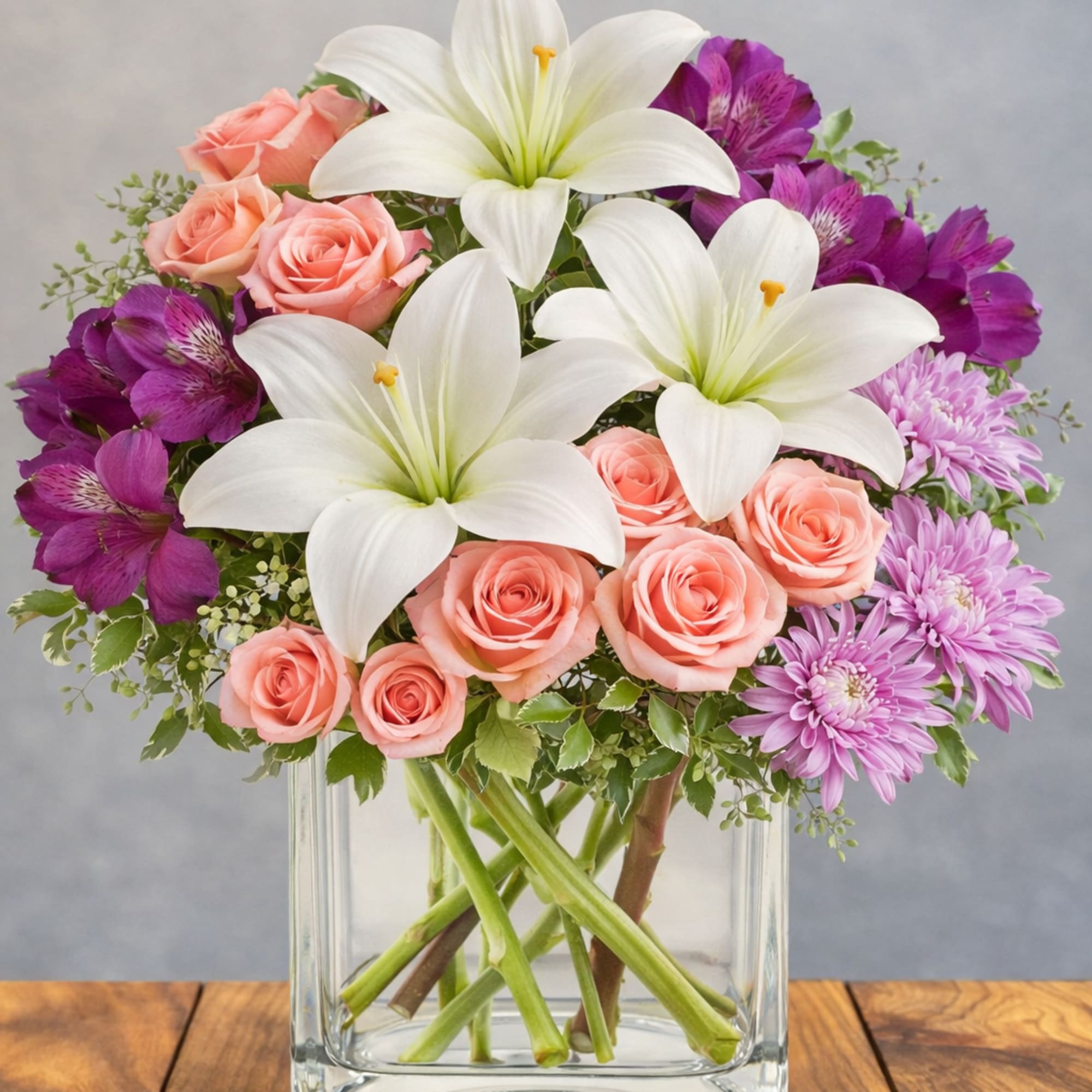 Soft pink roses and large white lilies mingle with vivid purple alstroemeria